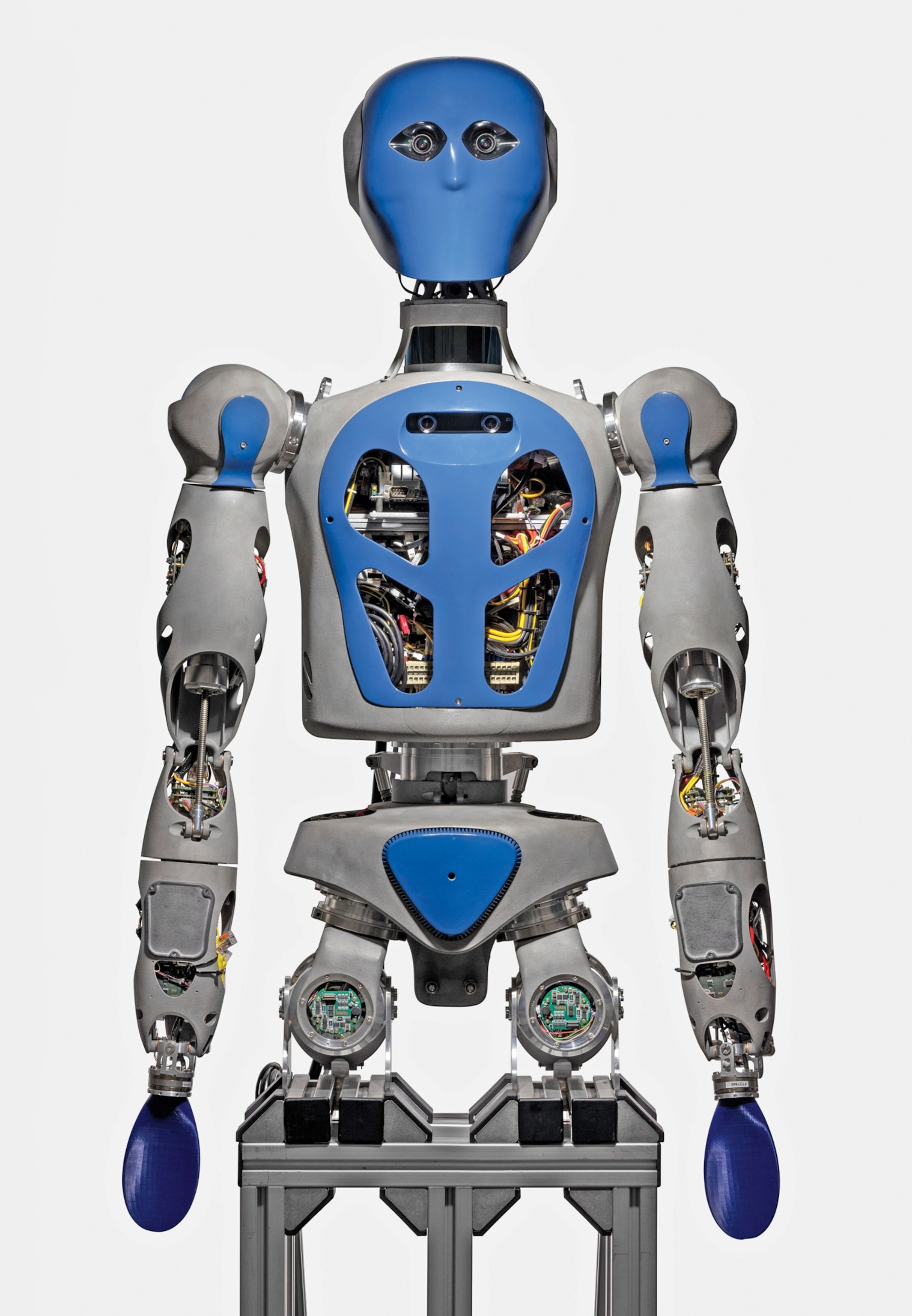 A humanoid robot with a blue and gray exterior is shown. Its torso reveals complex wiring and circuits