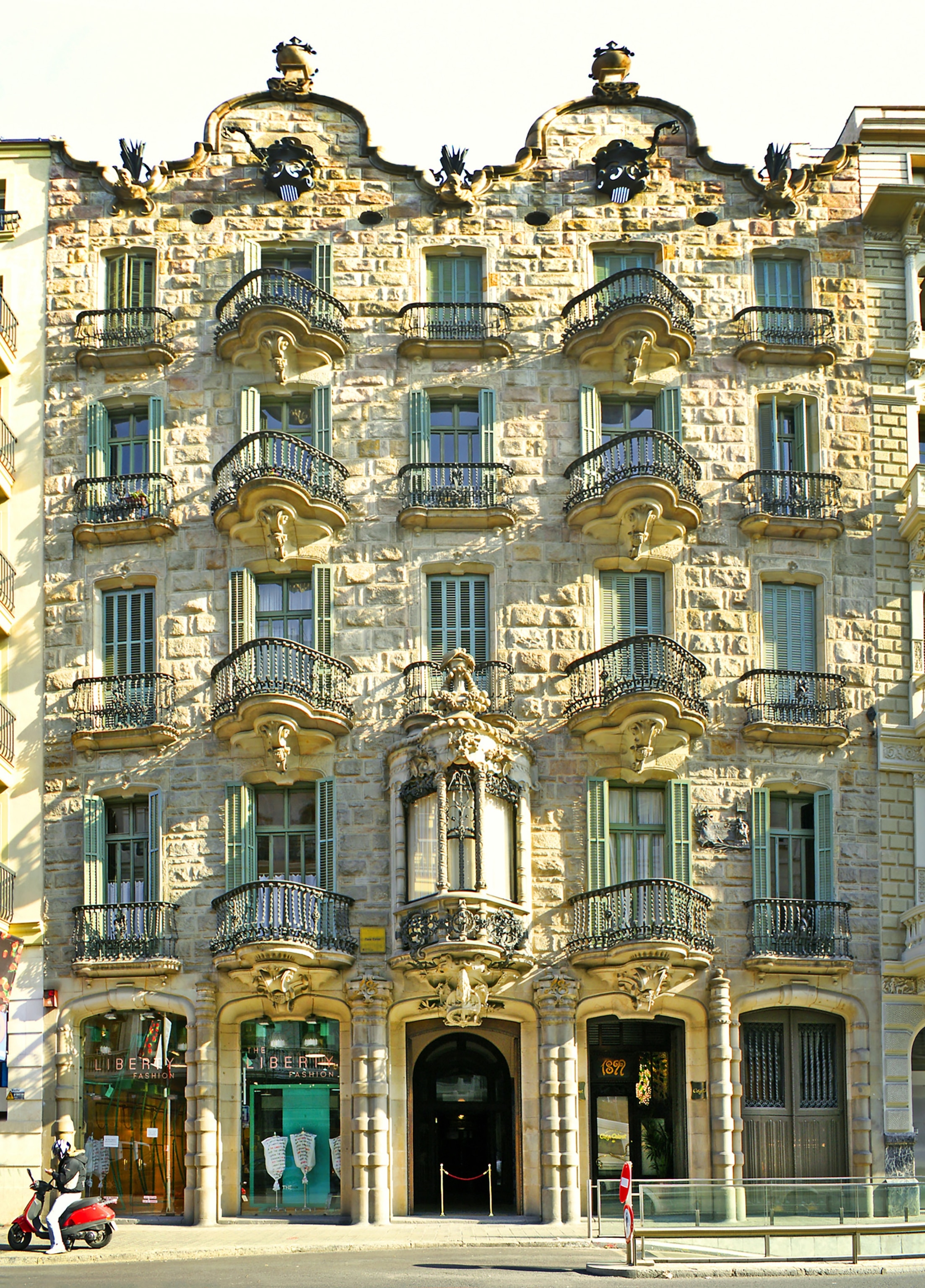 Facade of building with wrought-iron balconies and many windows, designed by Gaudi.