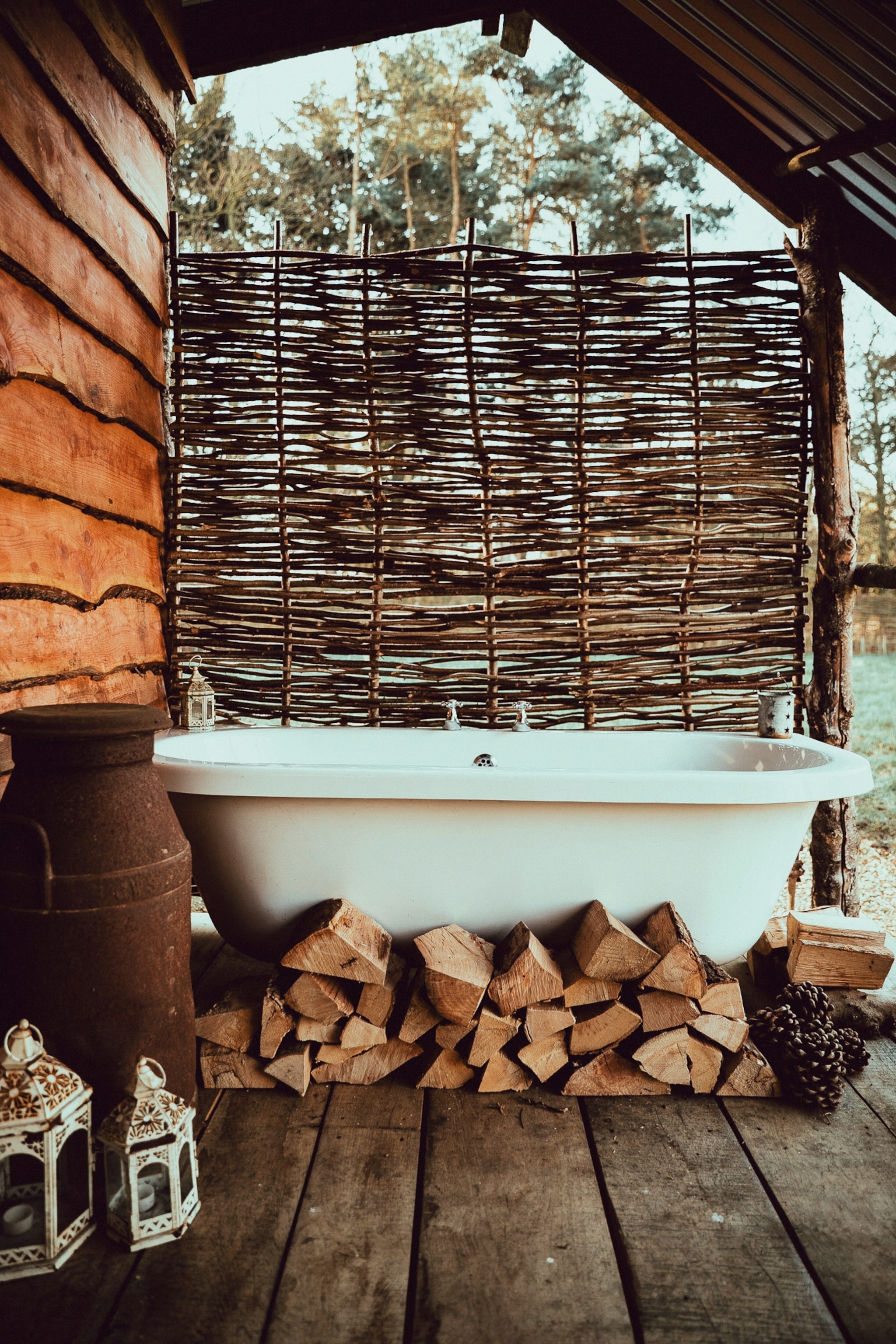 An outdoor bathtub surrounded by logs outside an off-grid cabin