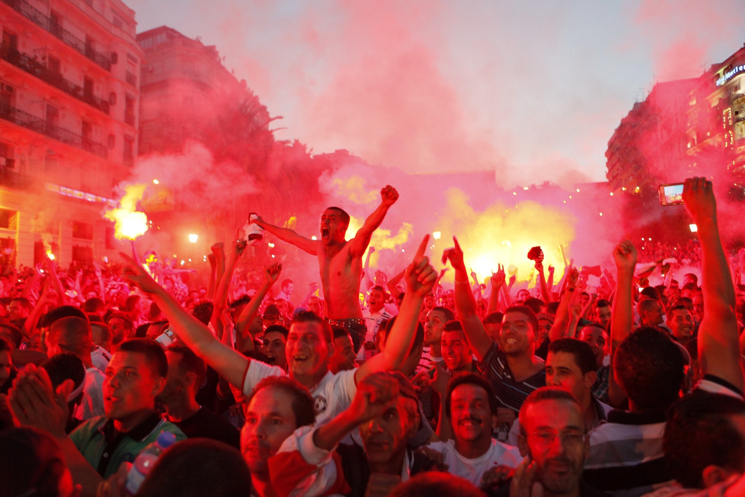 ALGIERS, ALGERIA - JUNE 22: Algeria's soccer fans celebrate their national team's victory against South Korea within the 2014 FIFA World Cup Brazil Group H, on giant screens in Algiers, June 22, 2014. Algeria won against South Korea 4-2 in 2014 FIFA World Cup Group H match played at Estadio Beira-Rio, Porto Alegre, Brazil. (Photo by Bechir Ramzy/Anadolu Agency/Getty Images)