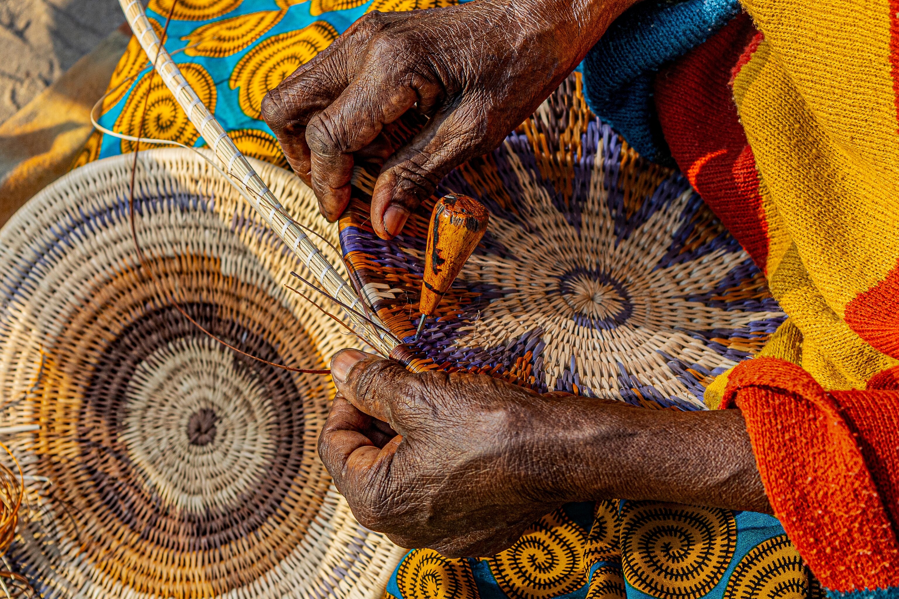 Village elder weaving traditional coiled baskets.
