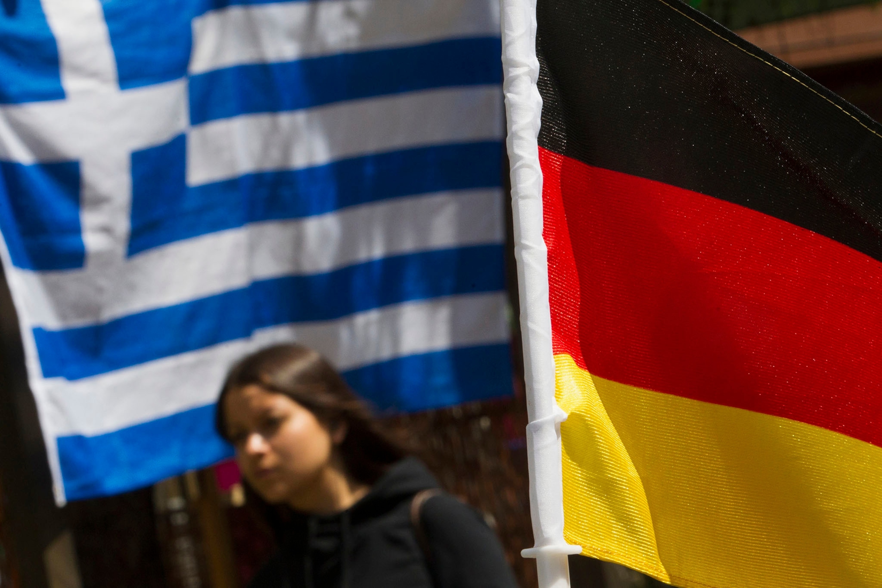 a woman as she walks past Greek and German national flags outside a Greek cafe in Berlin