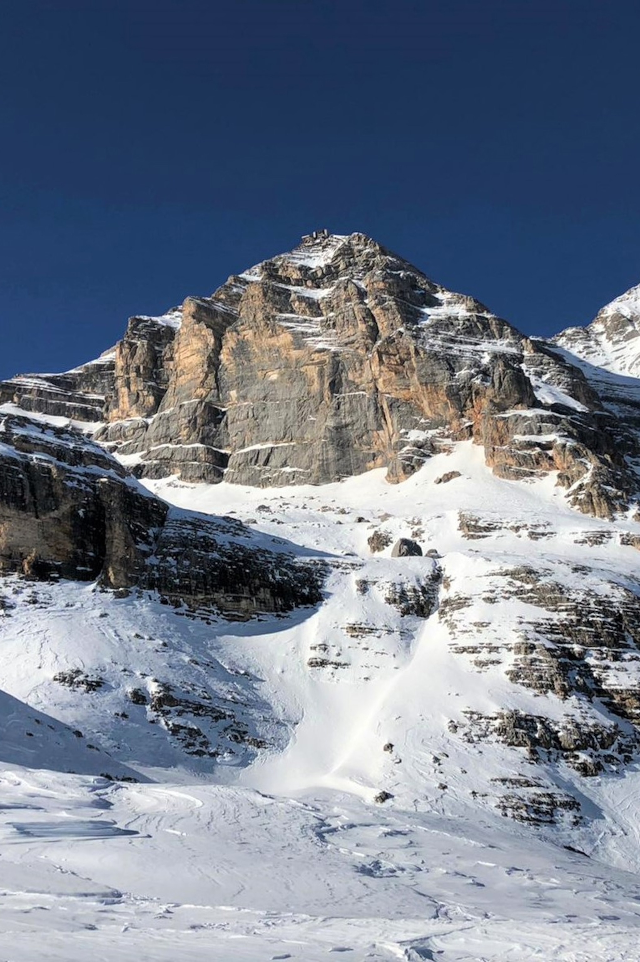 An exposed mount peak with a snowy valley below.