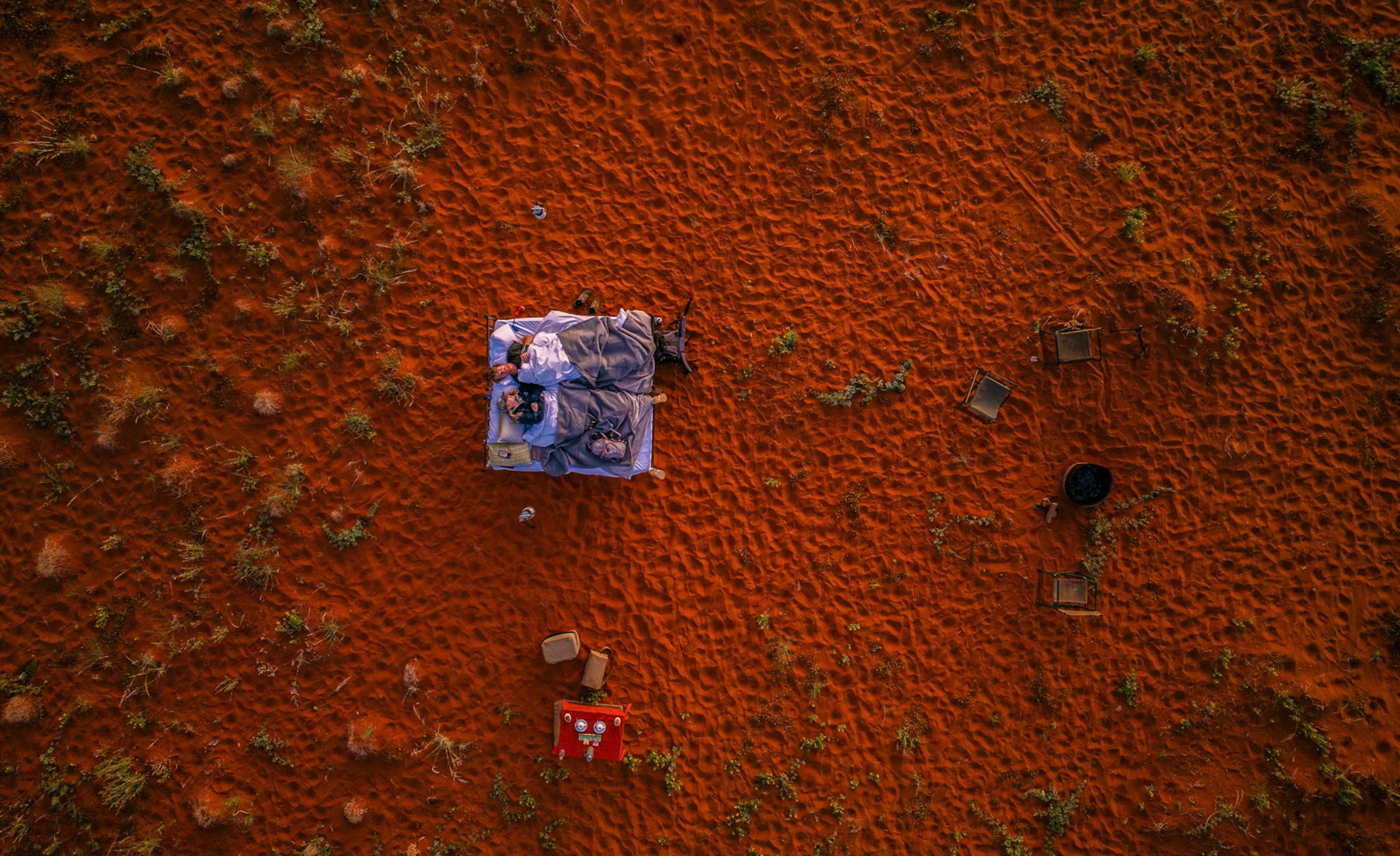 Two people lie in a bed in daylight on the NamibRand Nature Reserve