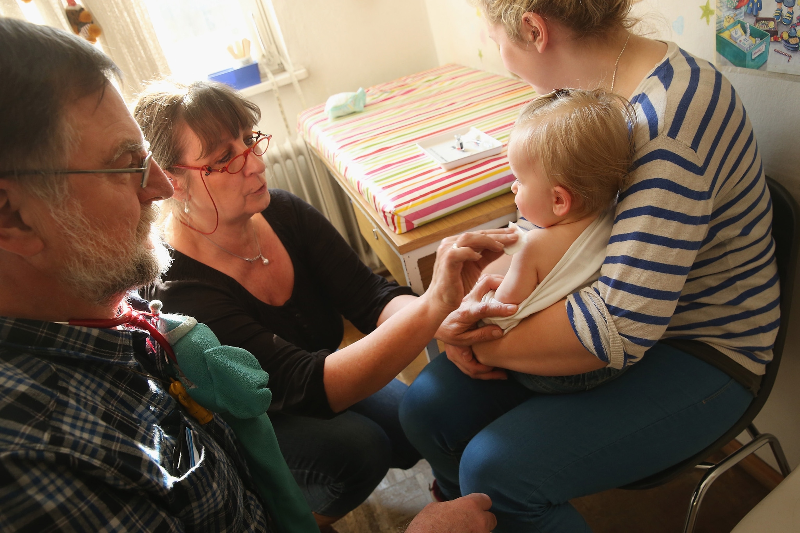 A doctor's assistant prepares 11-month-old Tijana for a vaccine