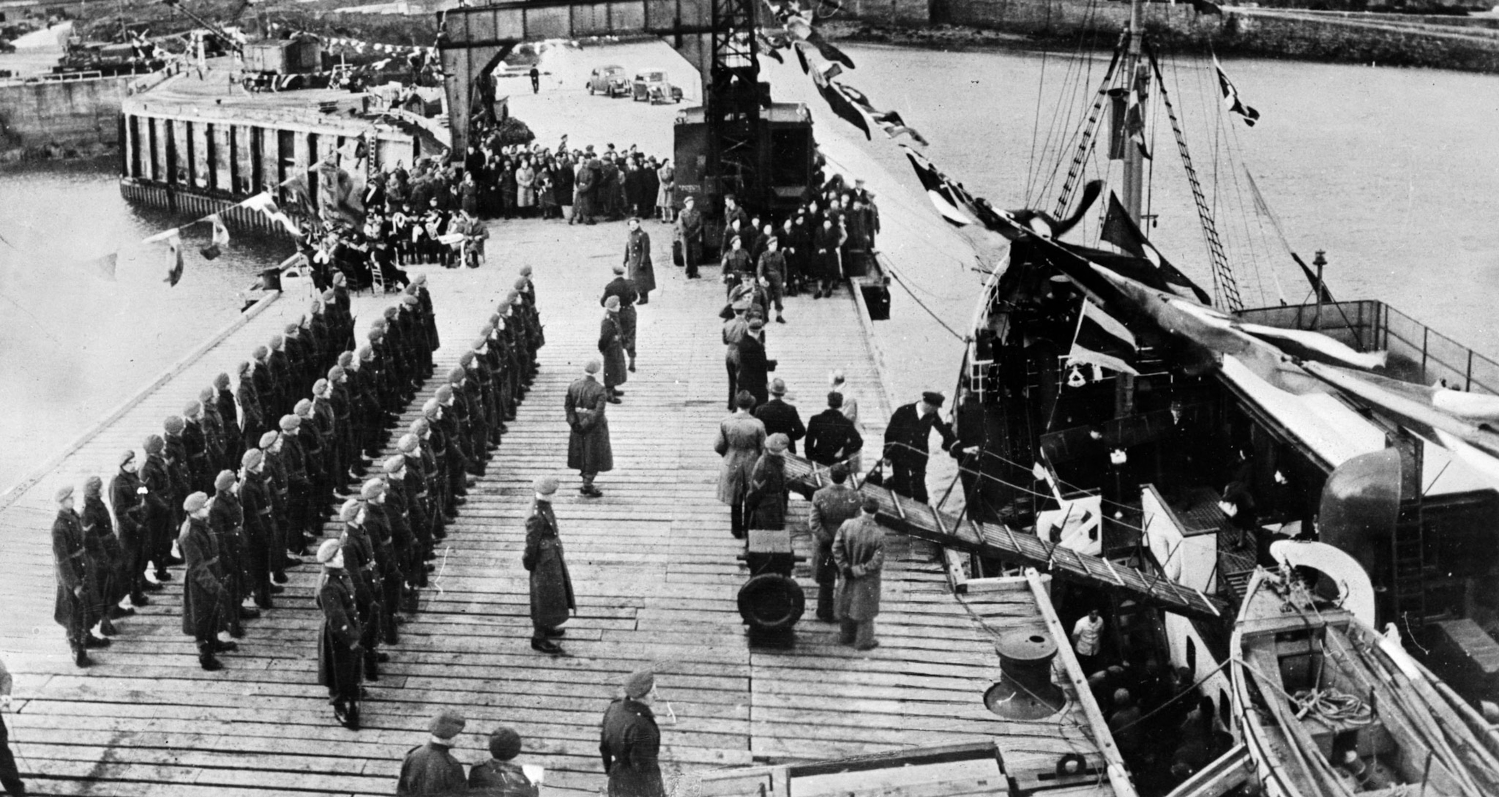 citizens getting off a boat with soldiers welcoming them standing at attention