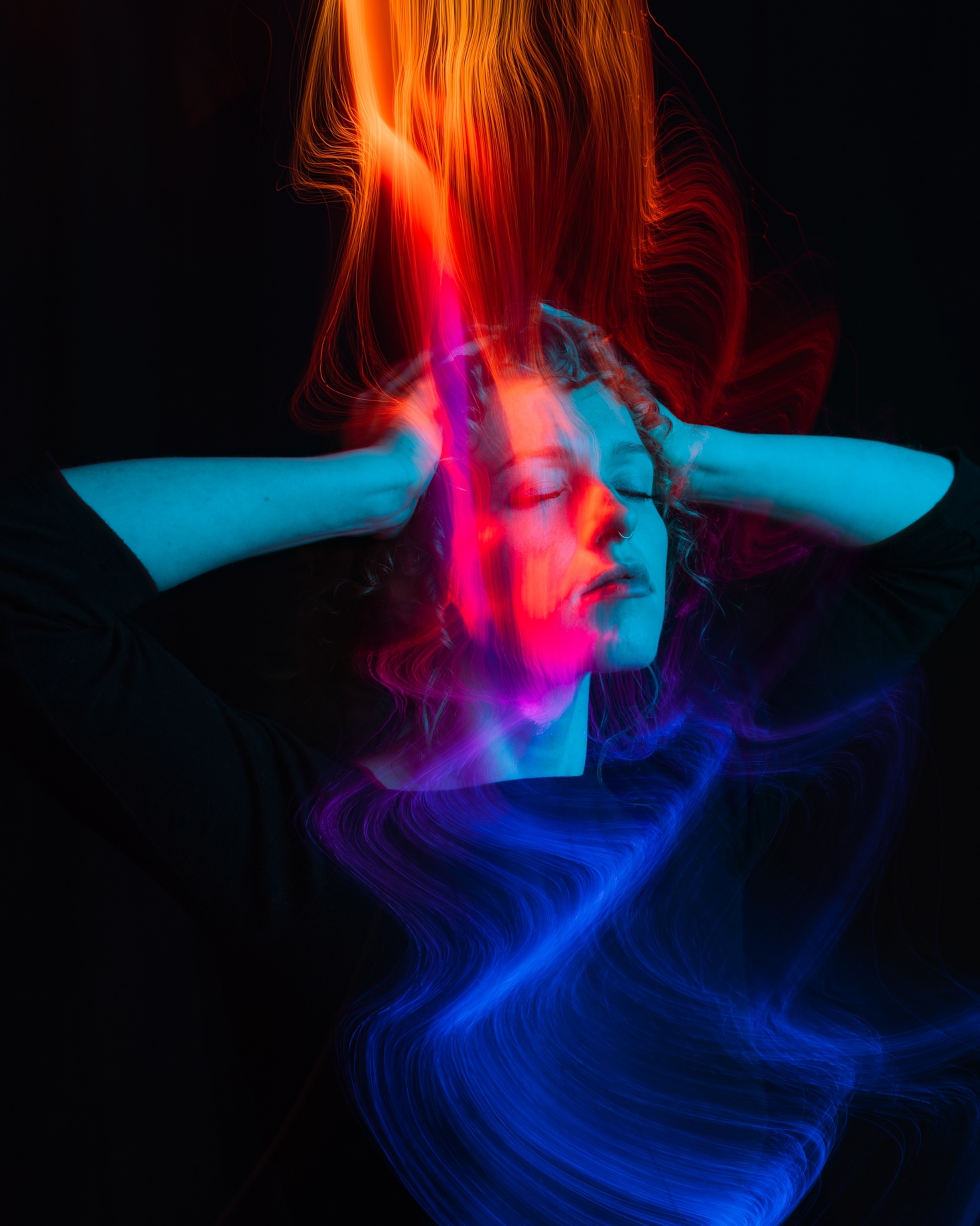 A person with eyes closed and hands on head in pain, surrounded by swirling orange and blue neon light