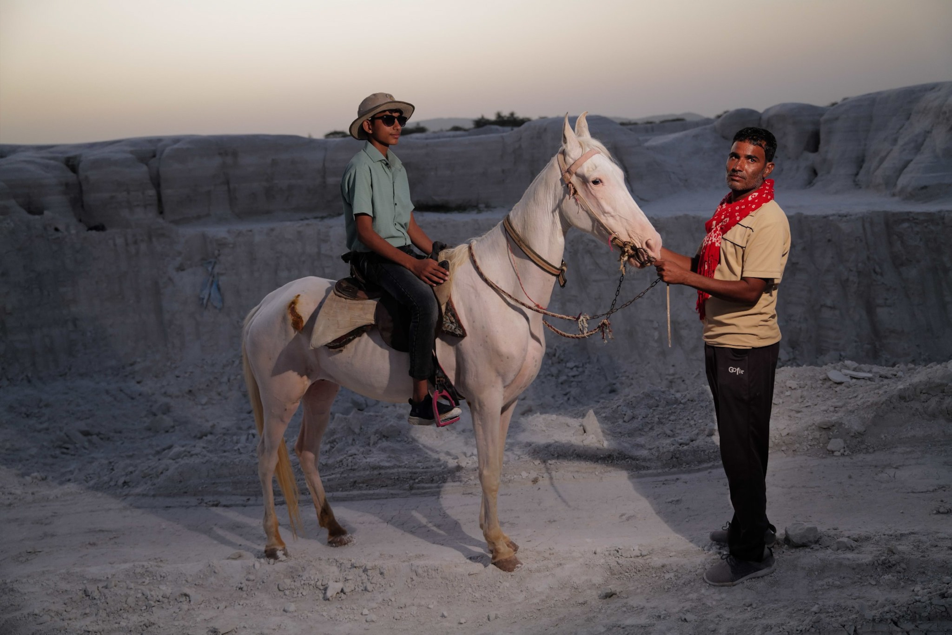 A boy sits on a horse and poses and a man holds the reins