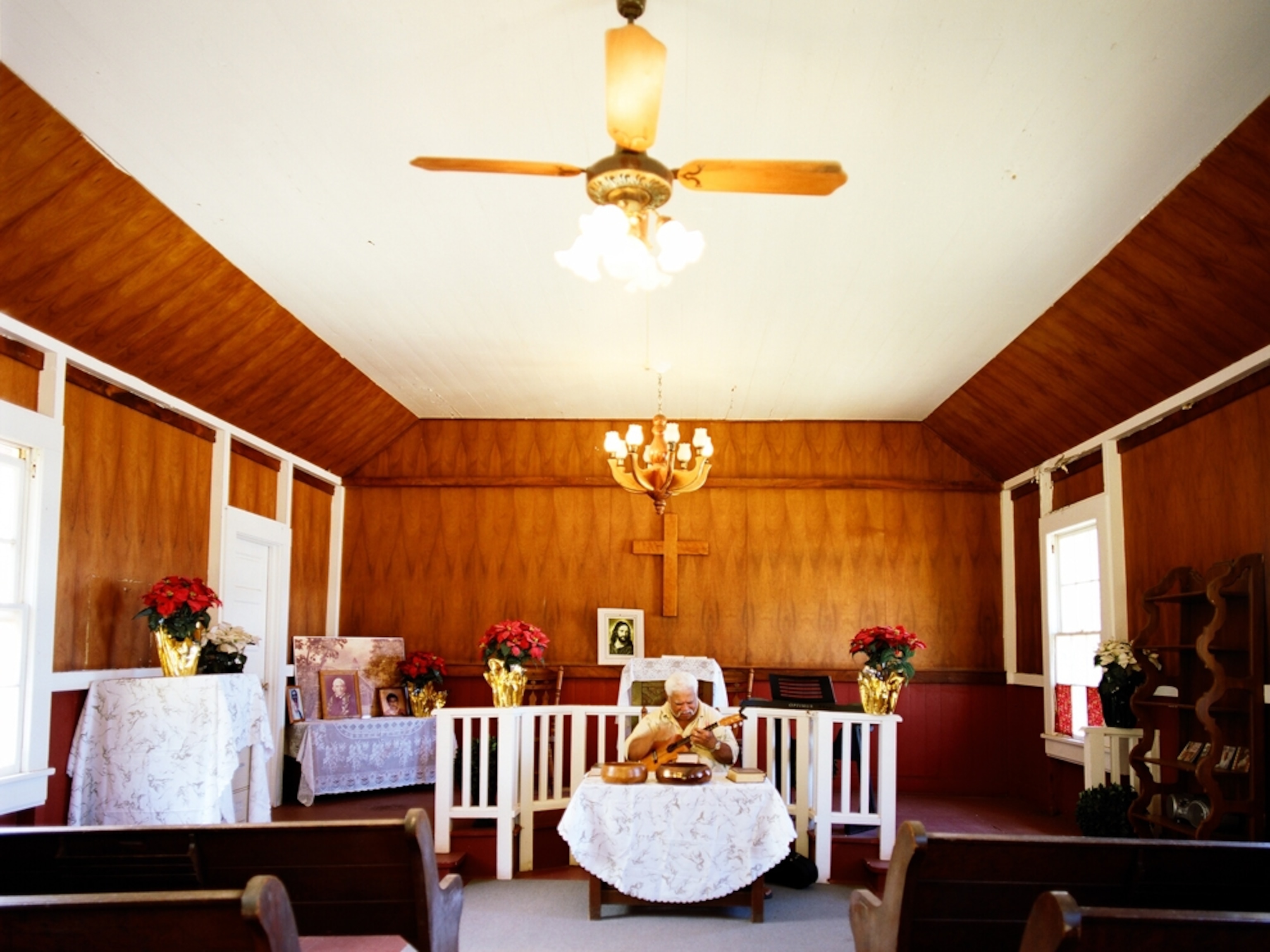 Uncle Richard Ho'opi'i, deacon of the church in Kahakuloa Village on the rugged North shore of West Maui, Hawaii, USA practices his ukulele and sings falsetto inside the church.