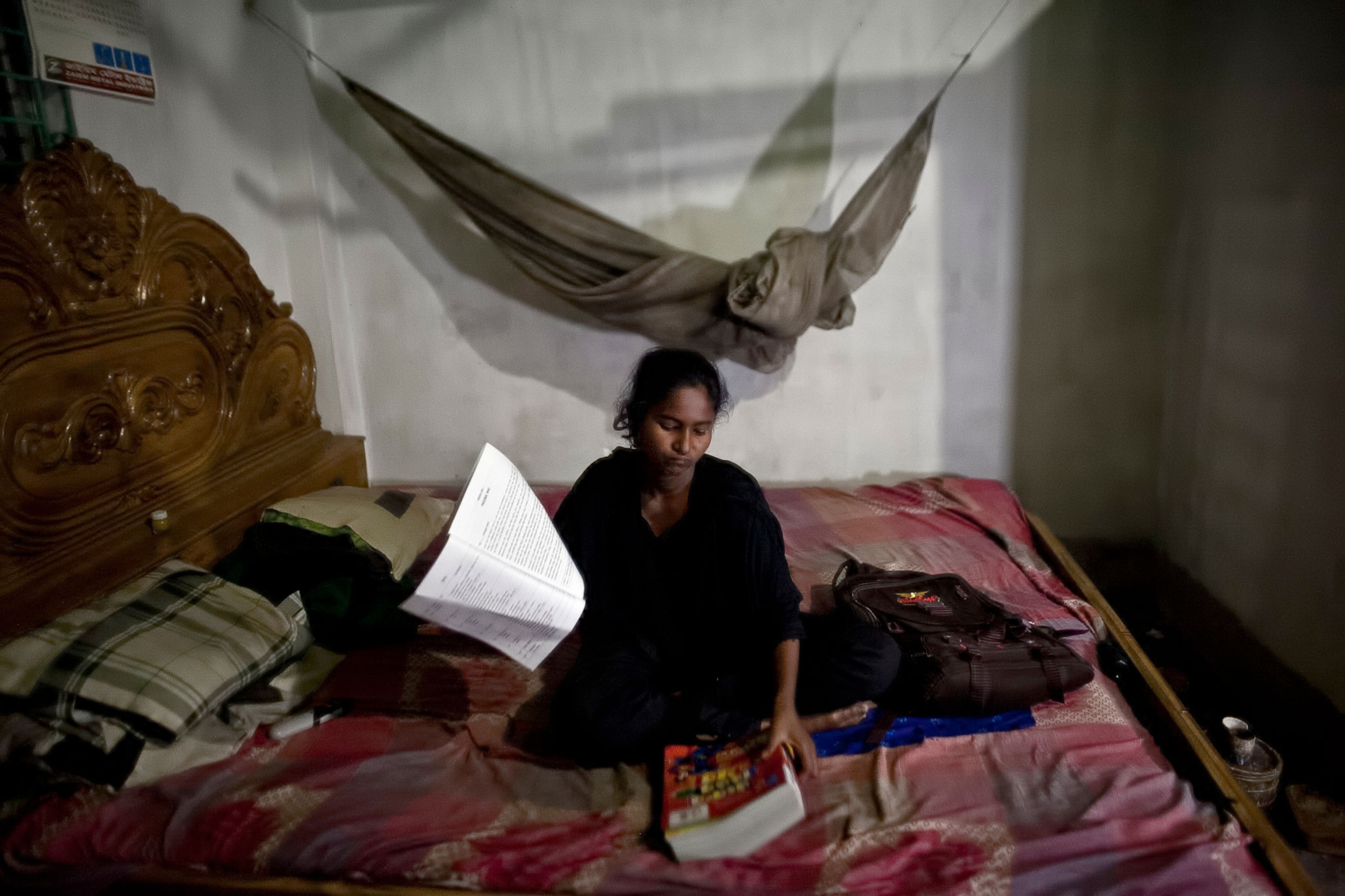 Sumi, who is the only girl able to go to a formal school, does her homework on her bed.