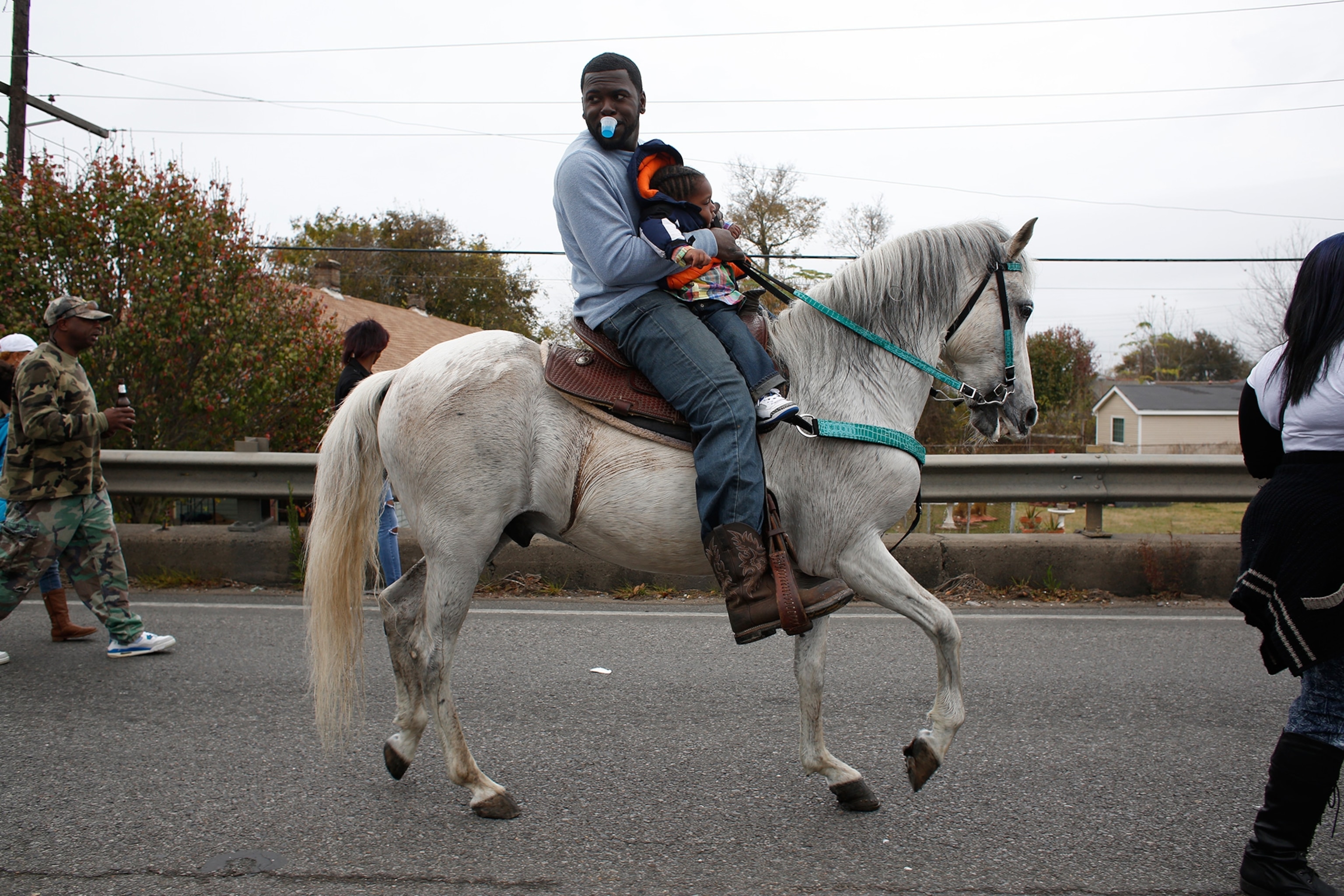 a man on horseback carrying a boy as they walk into the Lower Ninth Ward after crossing the St. Claude bridge in New Orleans.