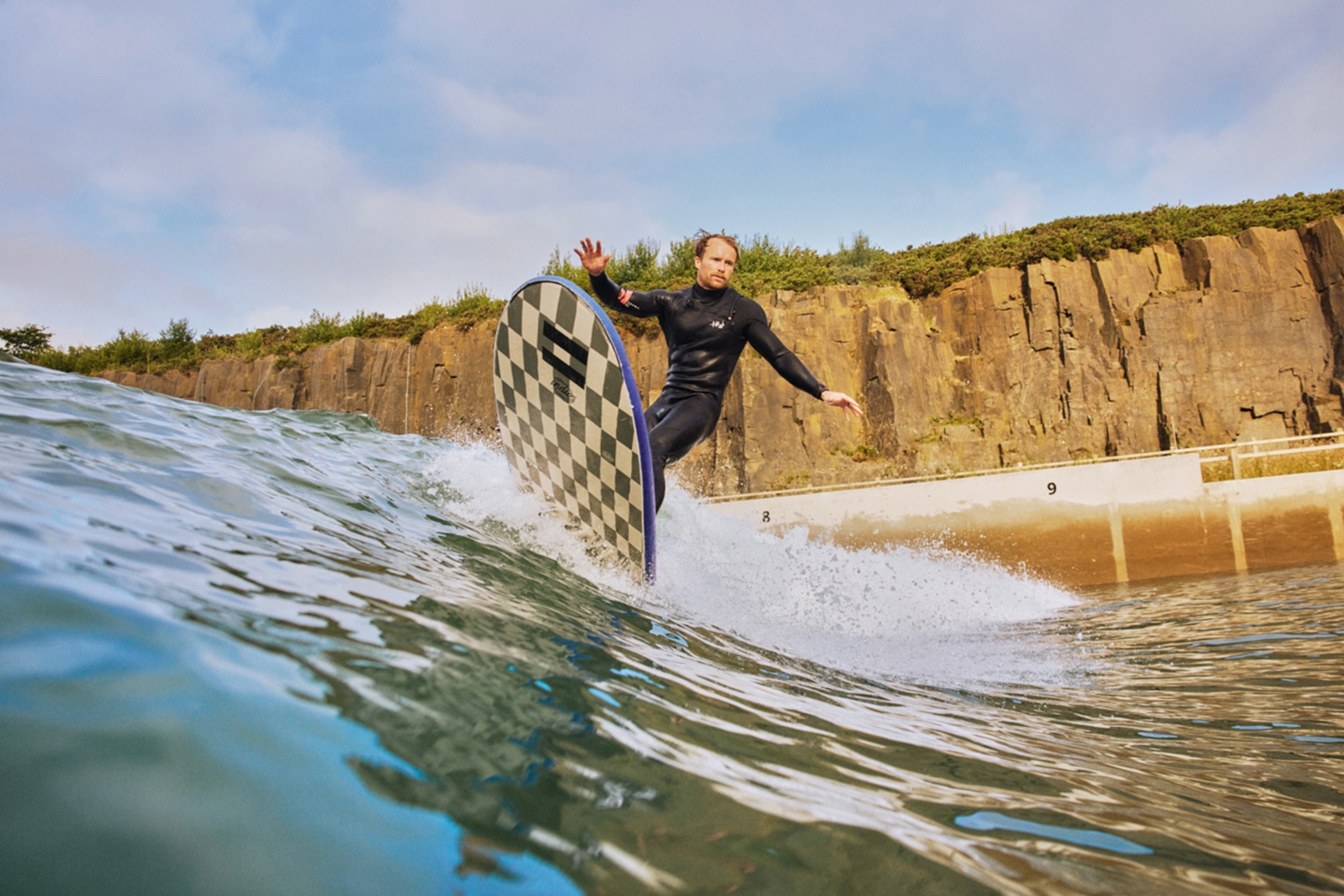 Man surfs wave in wetsuit.