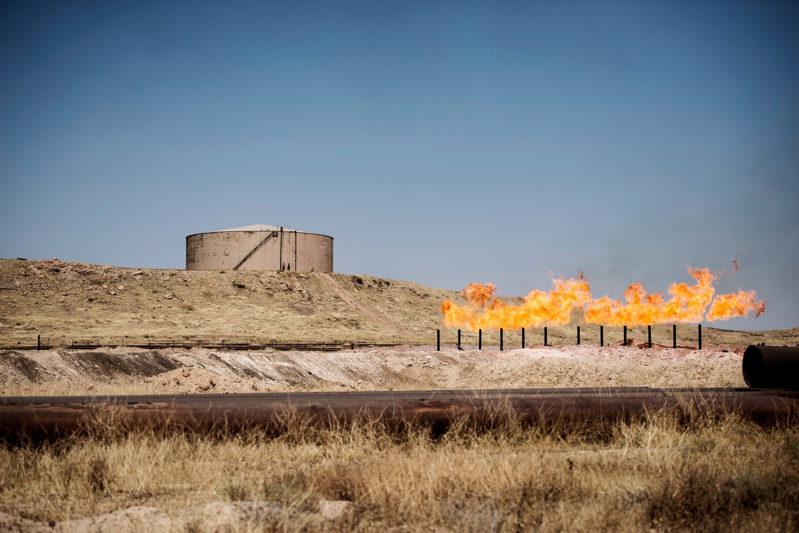 a gas flare burning near storage tanks in the oil fields near Kirkuk, Iraq.