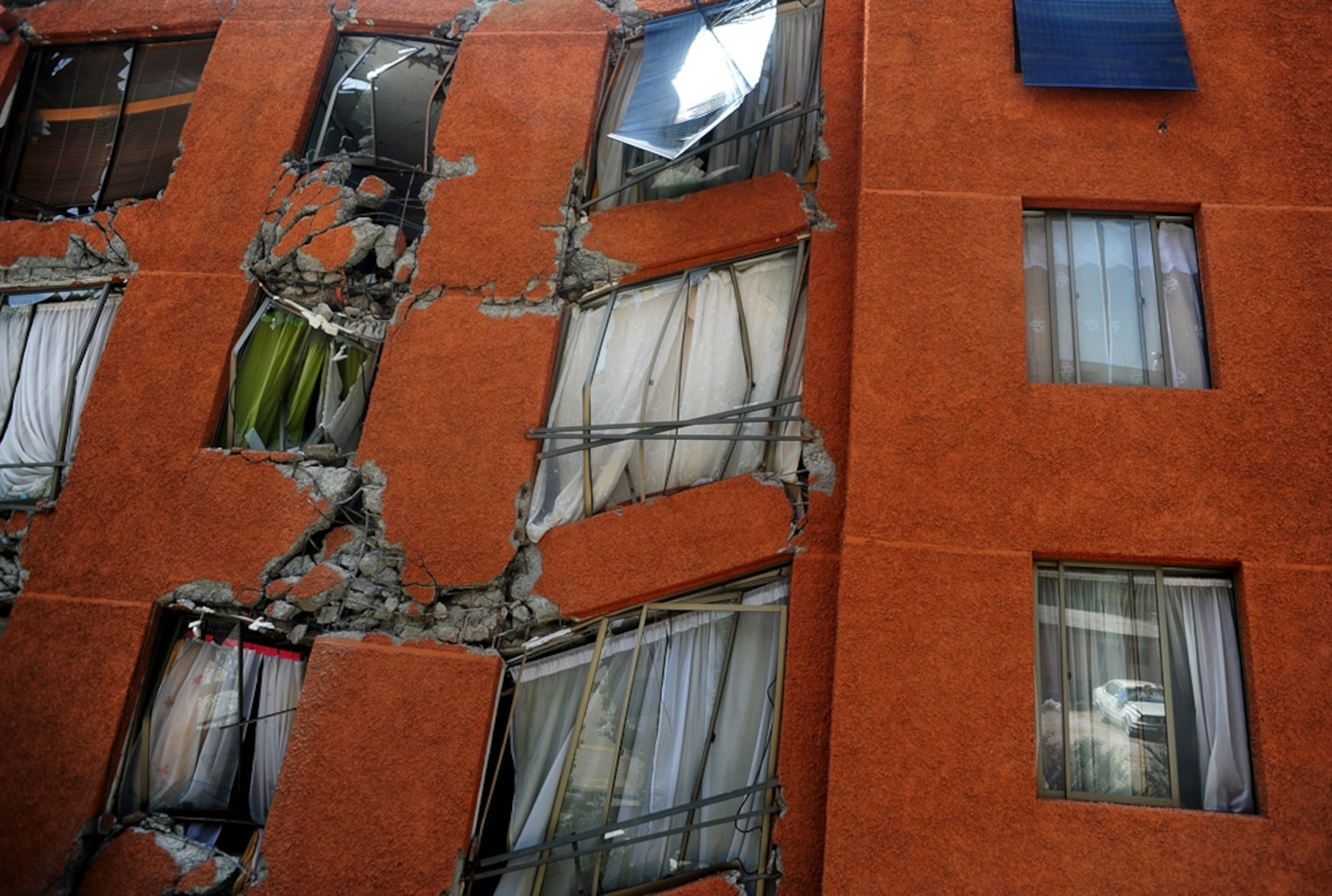 Windows of an apartment building are seen; damaged by the 2010 Chile earthquake, the structure has nearly toppled.