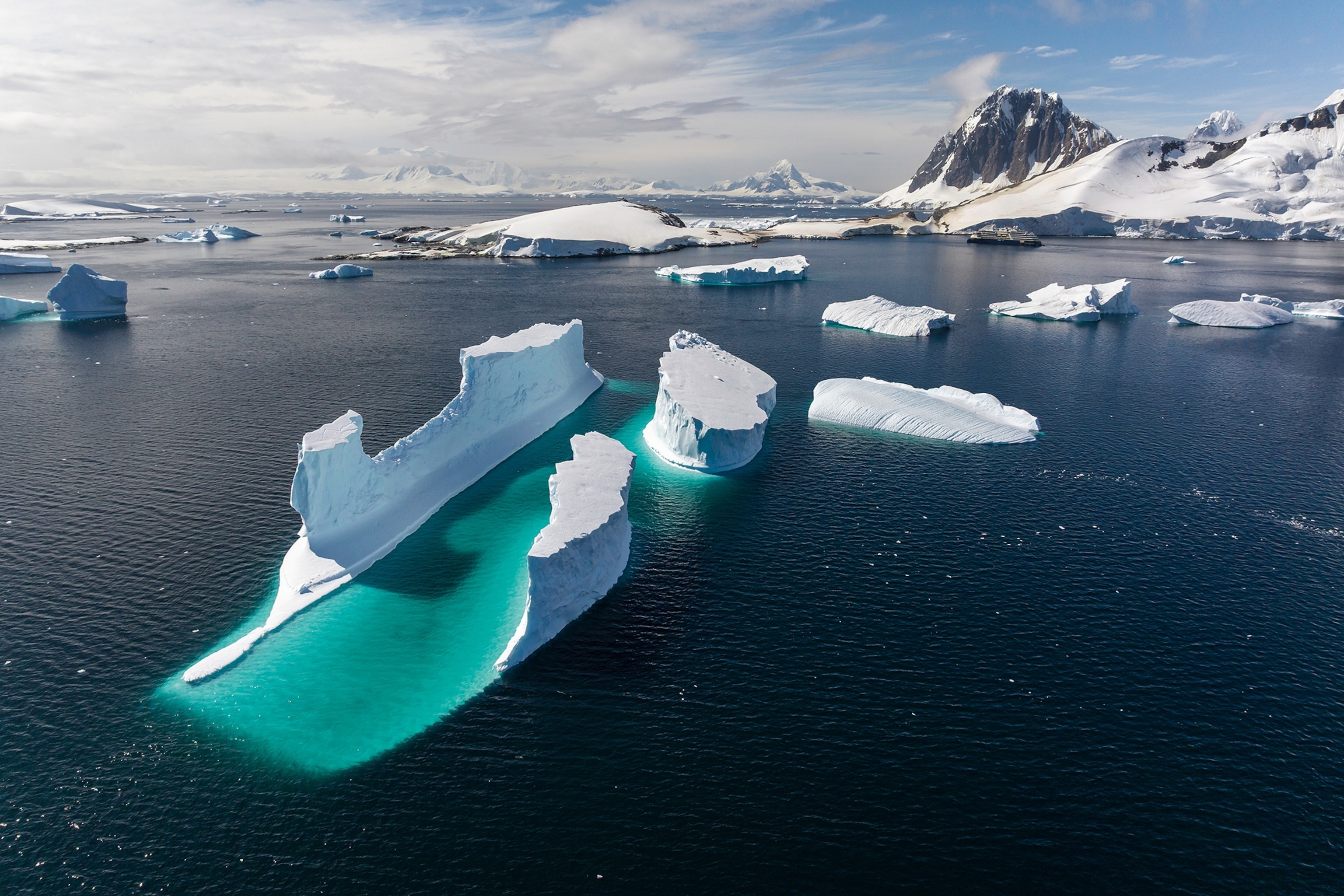 A wide shot of a sea in the Antarctic with a collection of icebergs floating aimlessly.