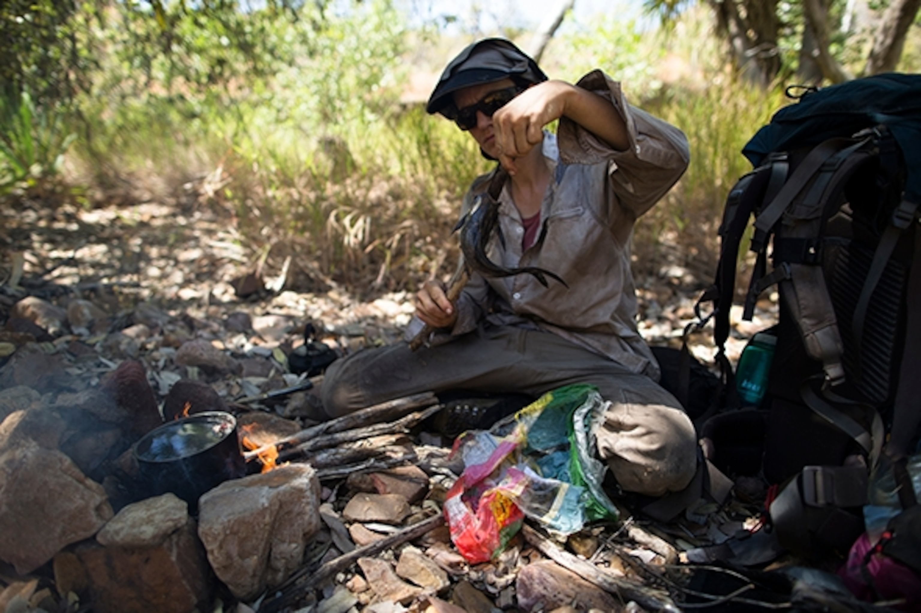 After a successful fishing venture, Marquis prepares the catfish to cook over a fire in the Osman Range. Catfish contains poisonous spikes which could potentially taint her other catch of black brim, which cook steadily in the pot; Photograph by Krystle Wright