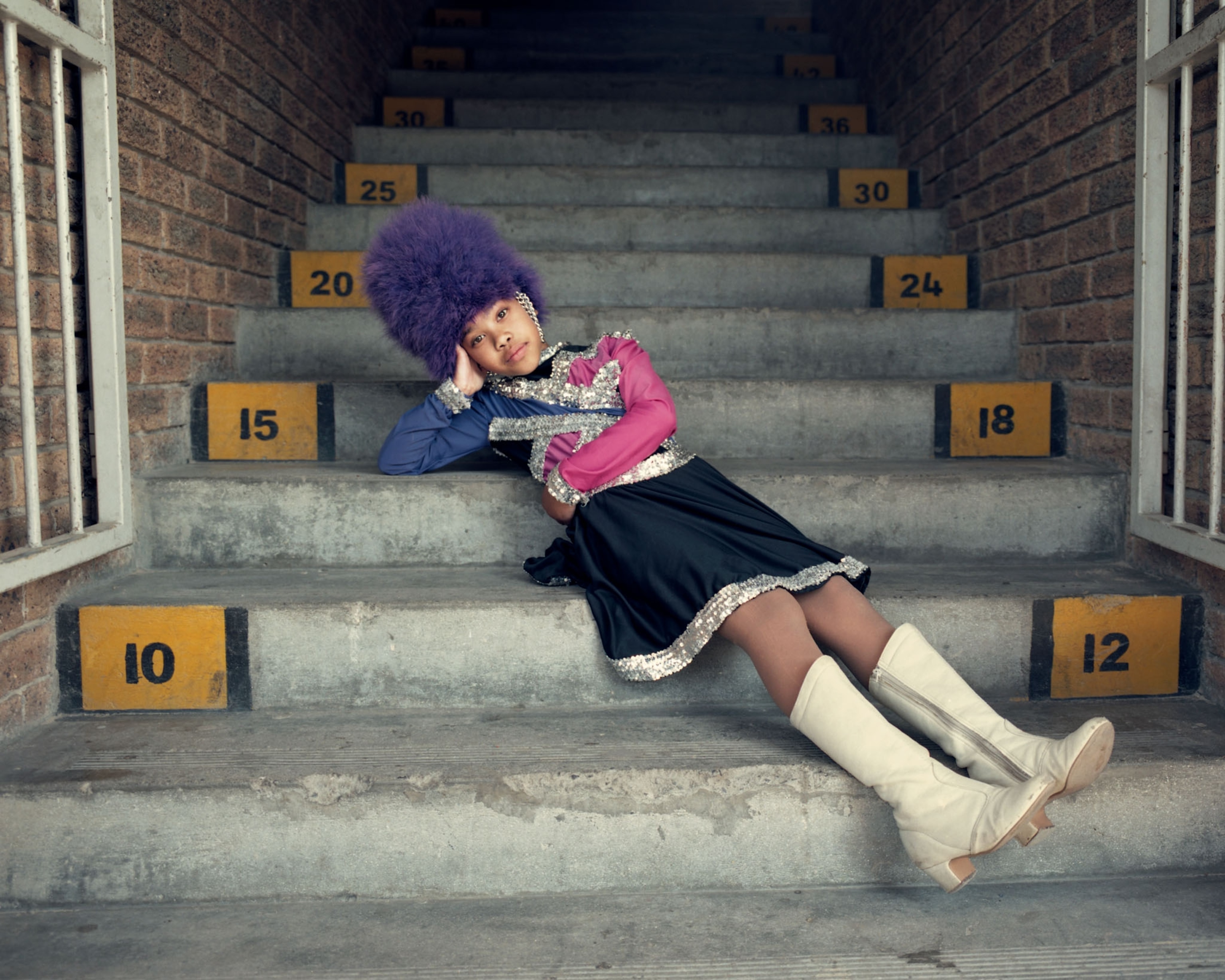 a young woman in a drum majorette uniform lounging on stairs