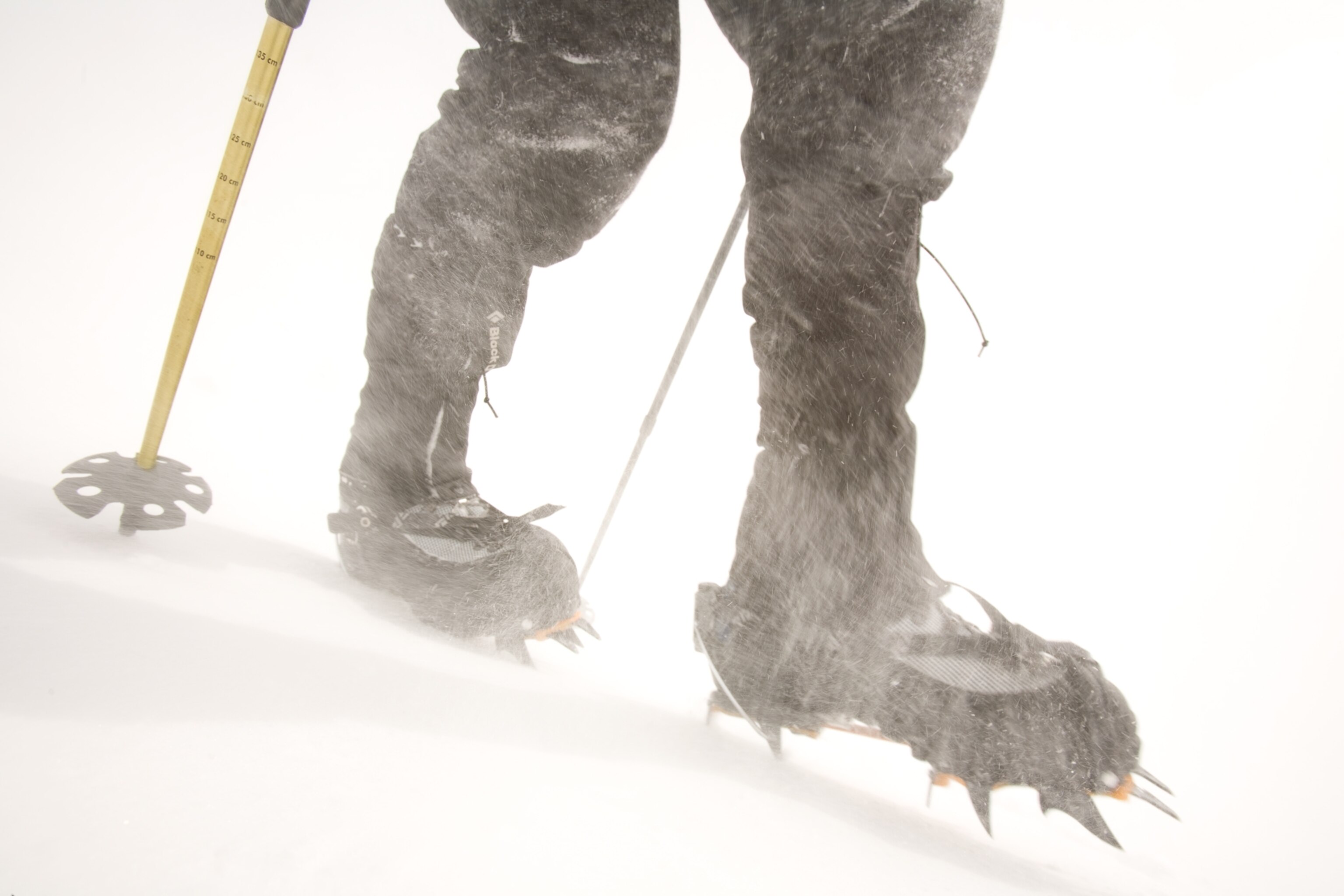 crampons and trekking poles helping a hiker through wind-driven ice and snow