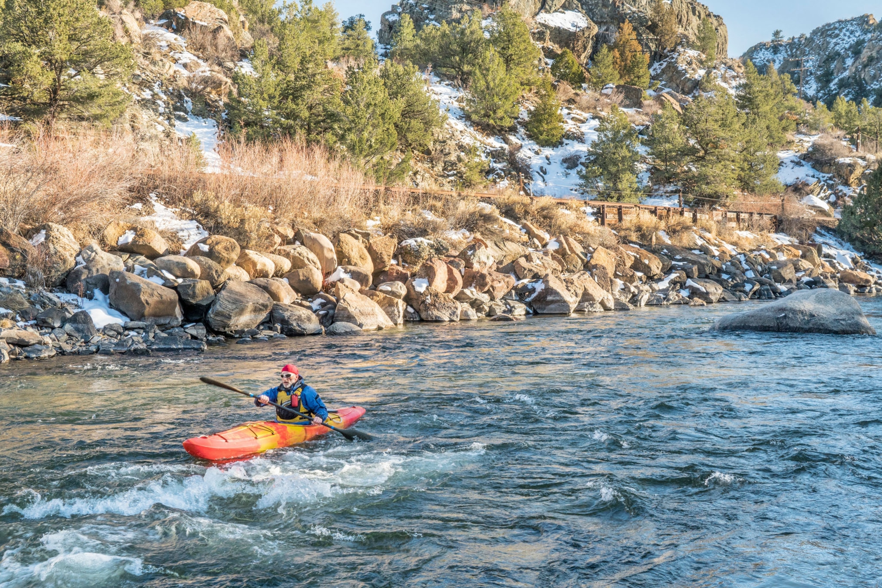 senior kayaker in a whitewater kayak paddling upstream - Arkansas River, Colorado in winter scenery