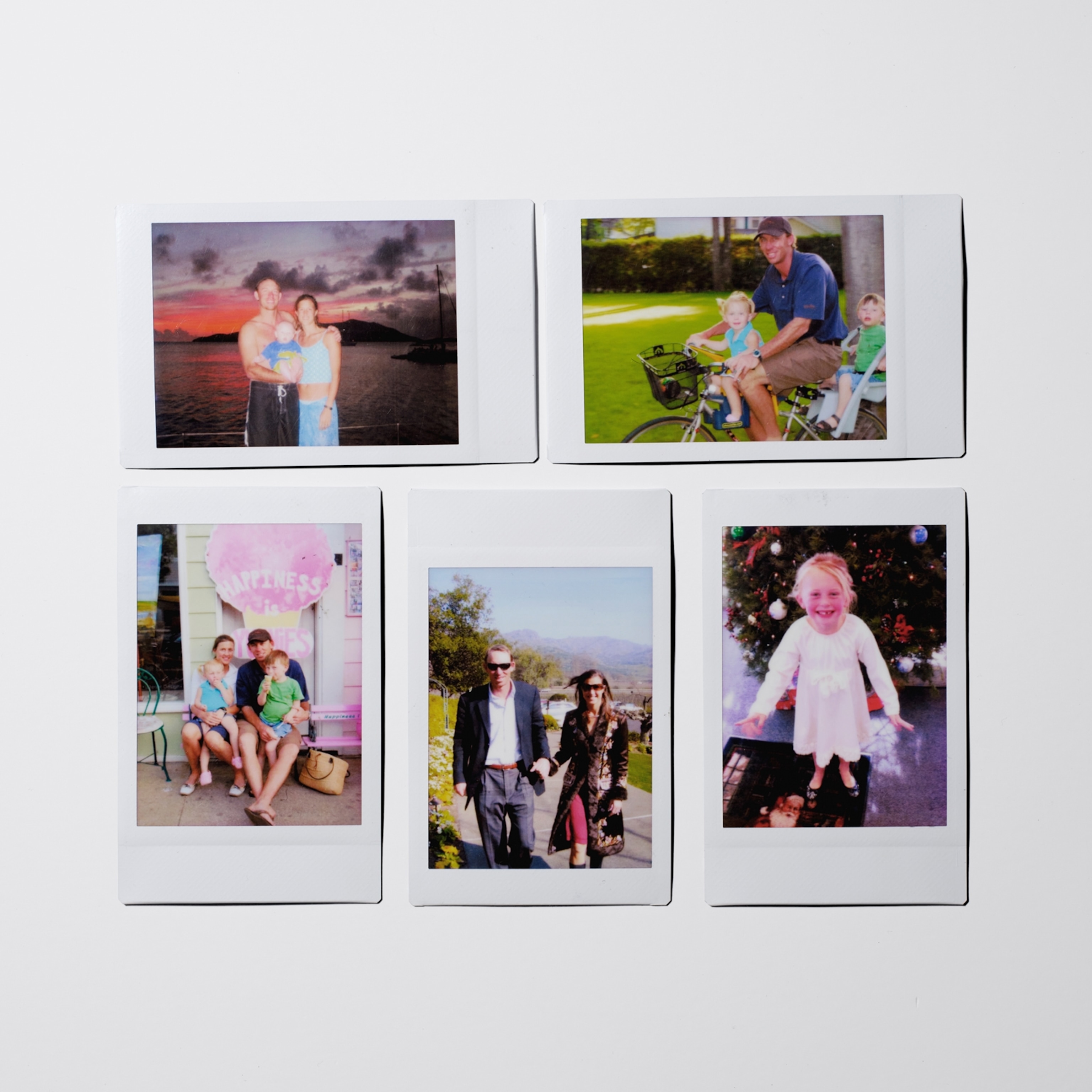 Five instant photographs laid out in two rows on a white background capture family moments: adults posing with young children by the water and outside a shop, a bicycle ride with two children, two adults walking outdoors, and a child standing in front of a decorated Christmas tree.
