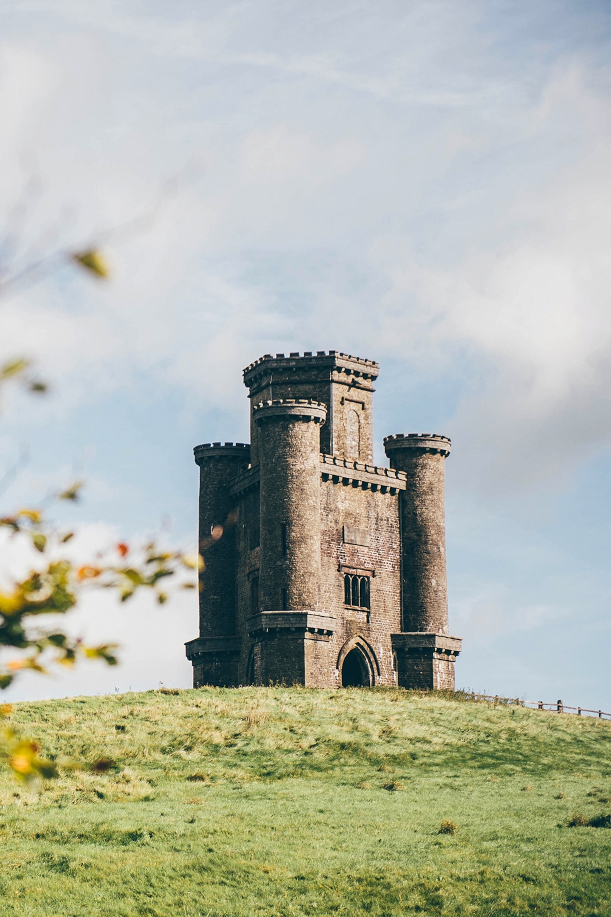 A tall, stone tower standing on the top of a hill.