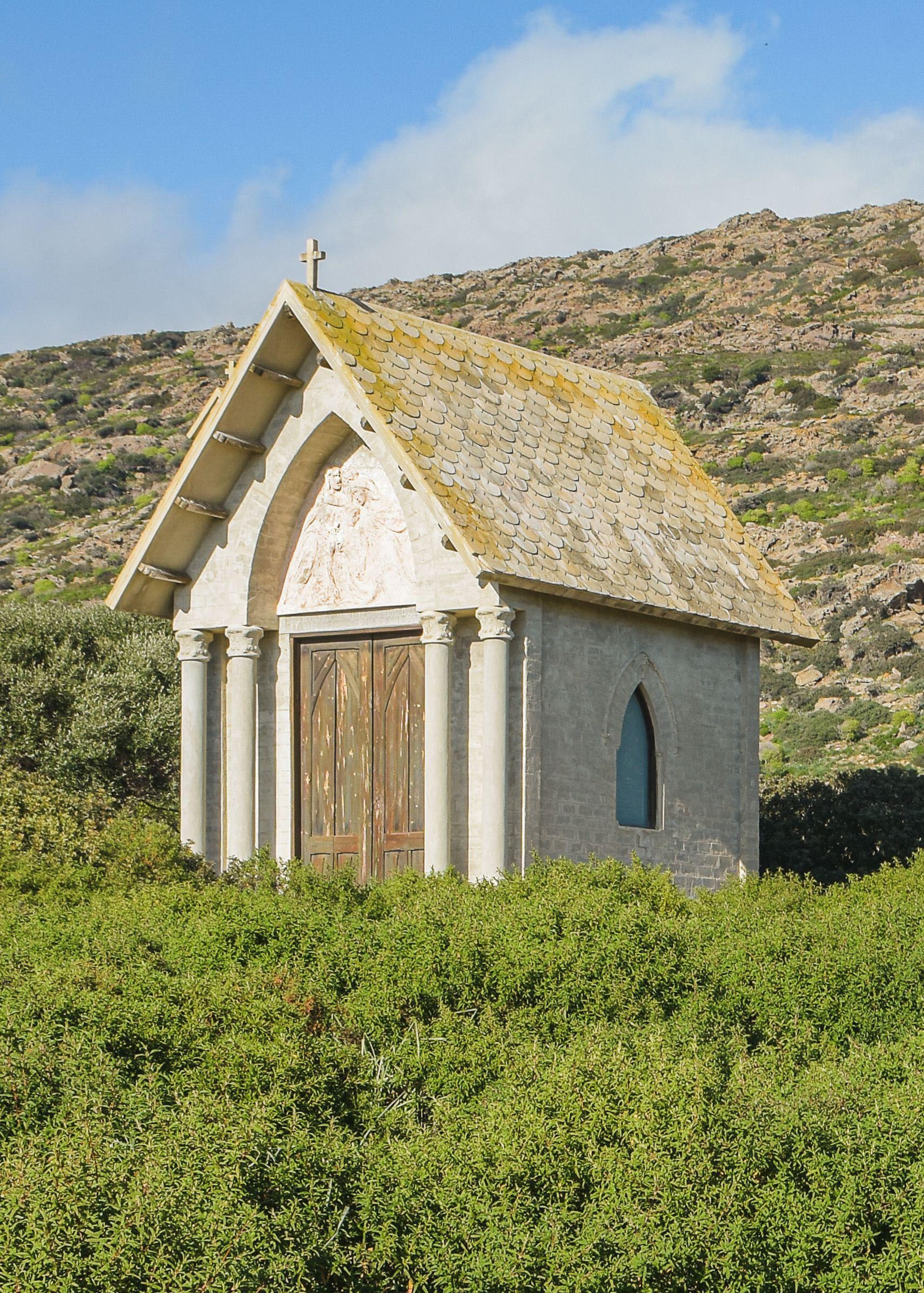 A small white chapel sits atop a green hill.