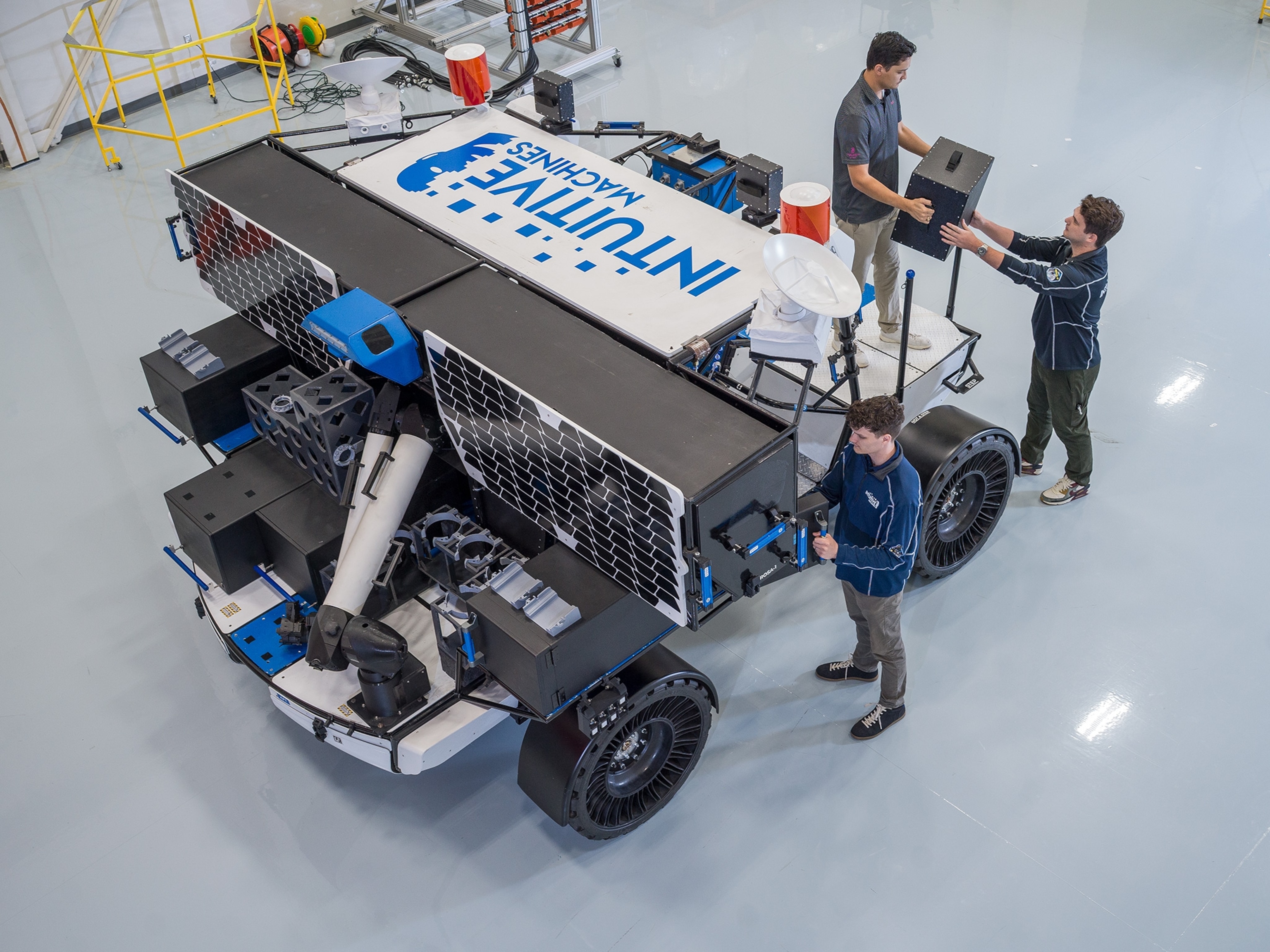 looking from above a 4x4 in a warehouse with three people standing around