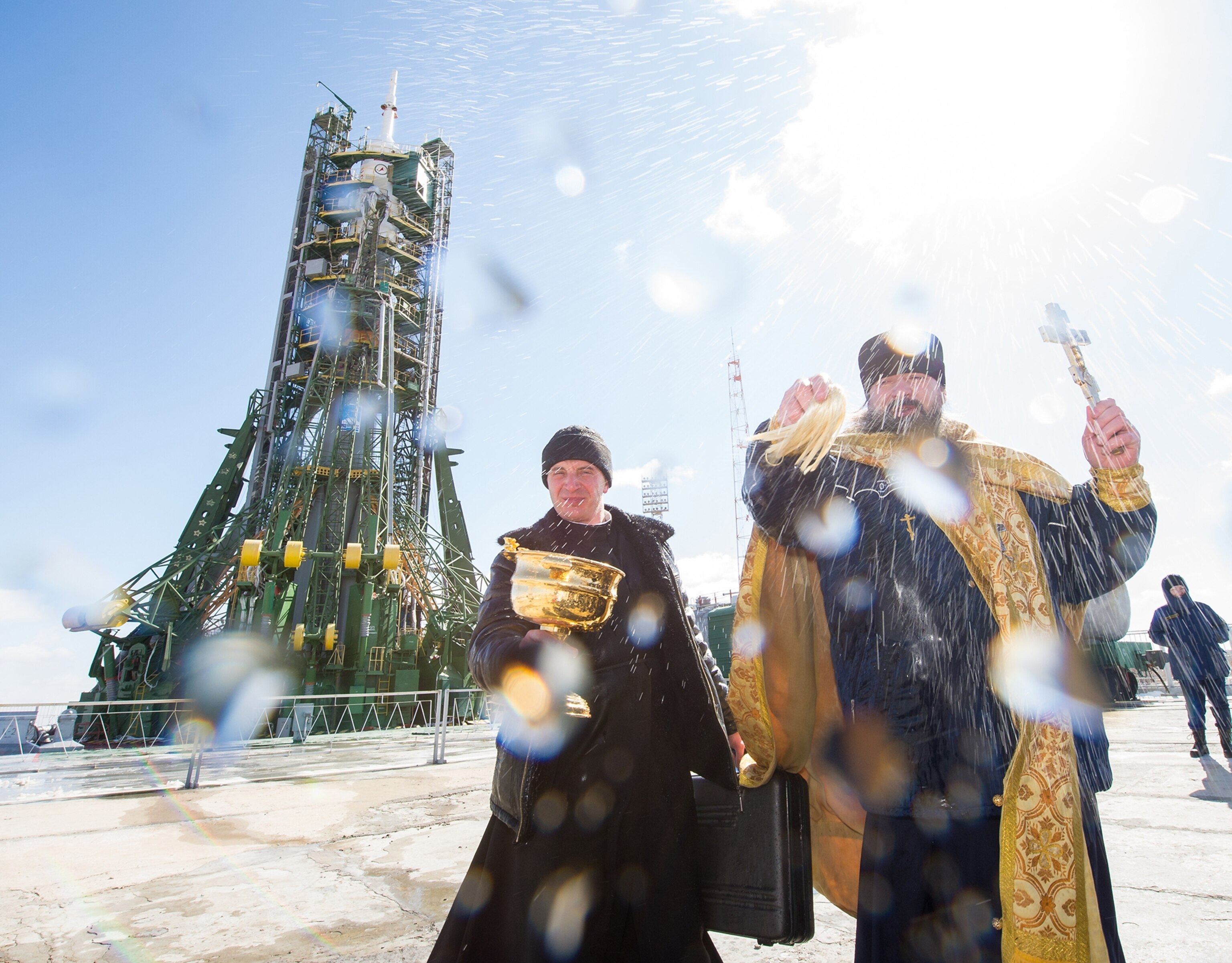 Orthodox priests sprinkling holy water near rocket ship