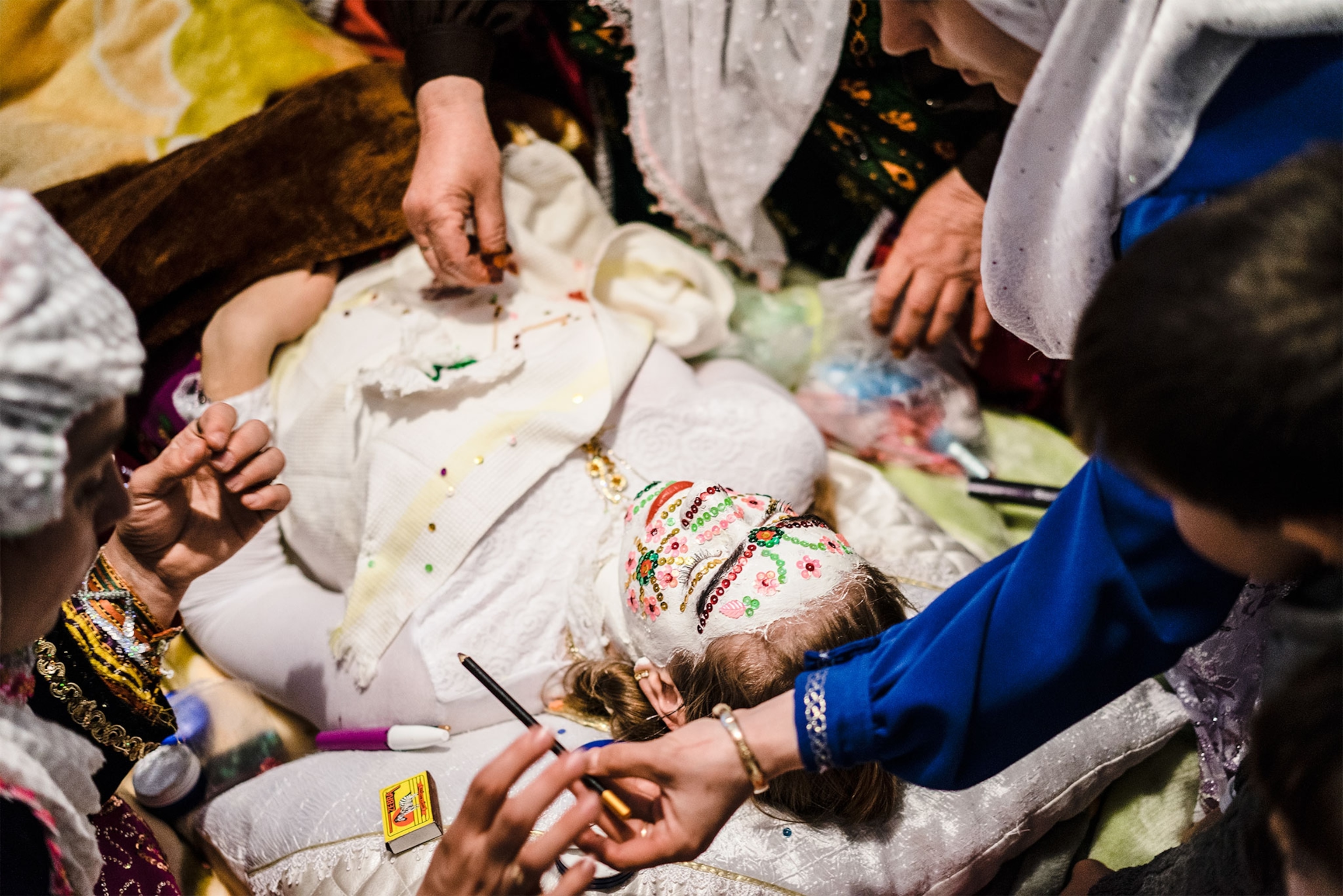 female relatives painting a bride during a ceremony