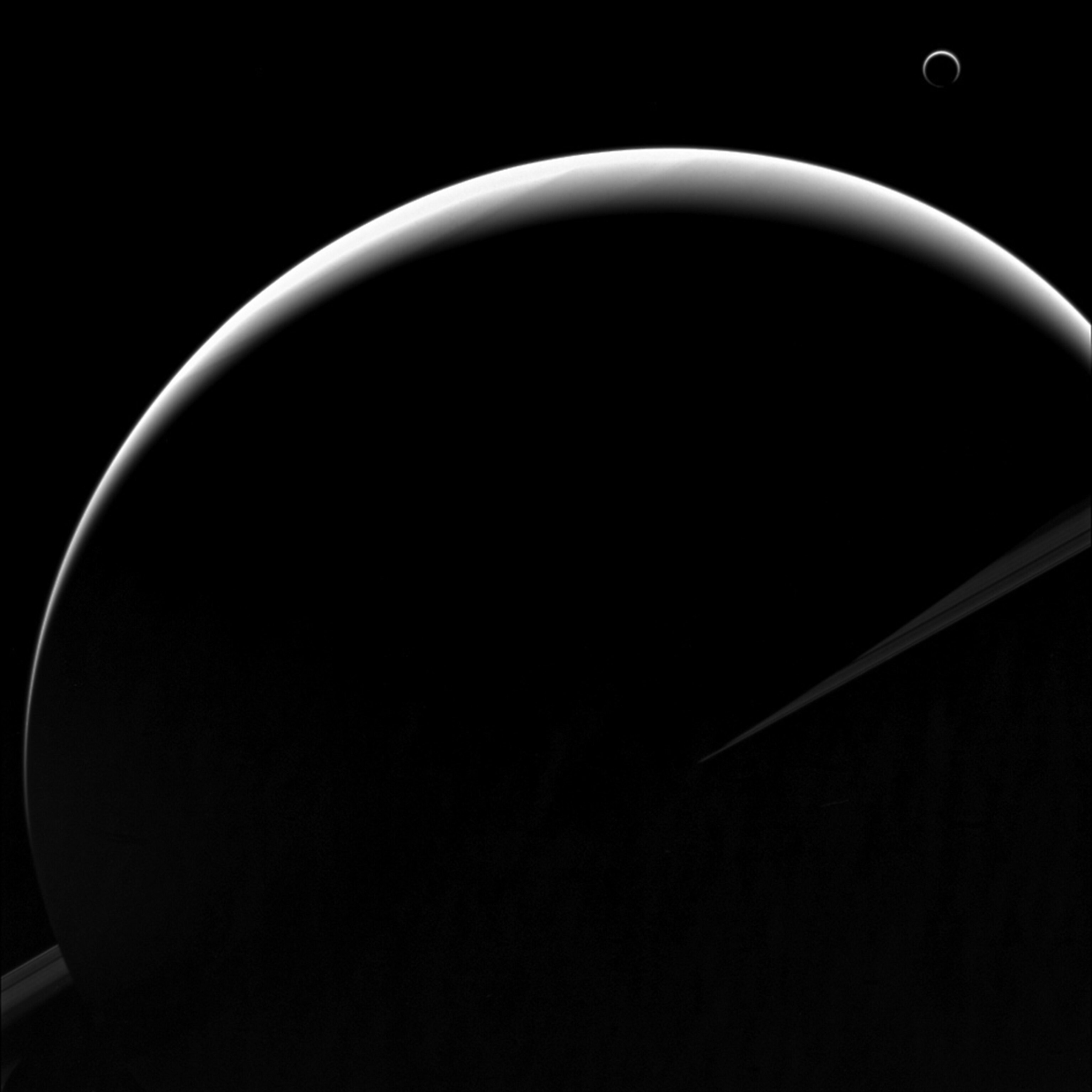 Saturn's moon Titan's crescent nearly encircles its disk due to the small haze particles high in its atmosphere scattering the incoming light of the distant Sun.