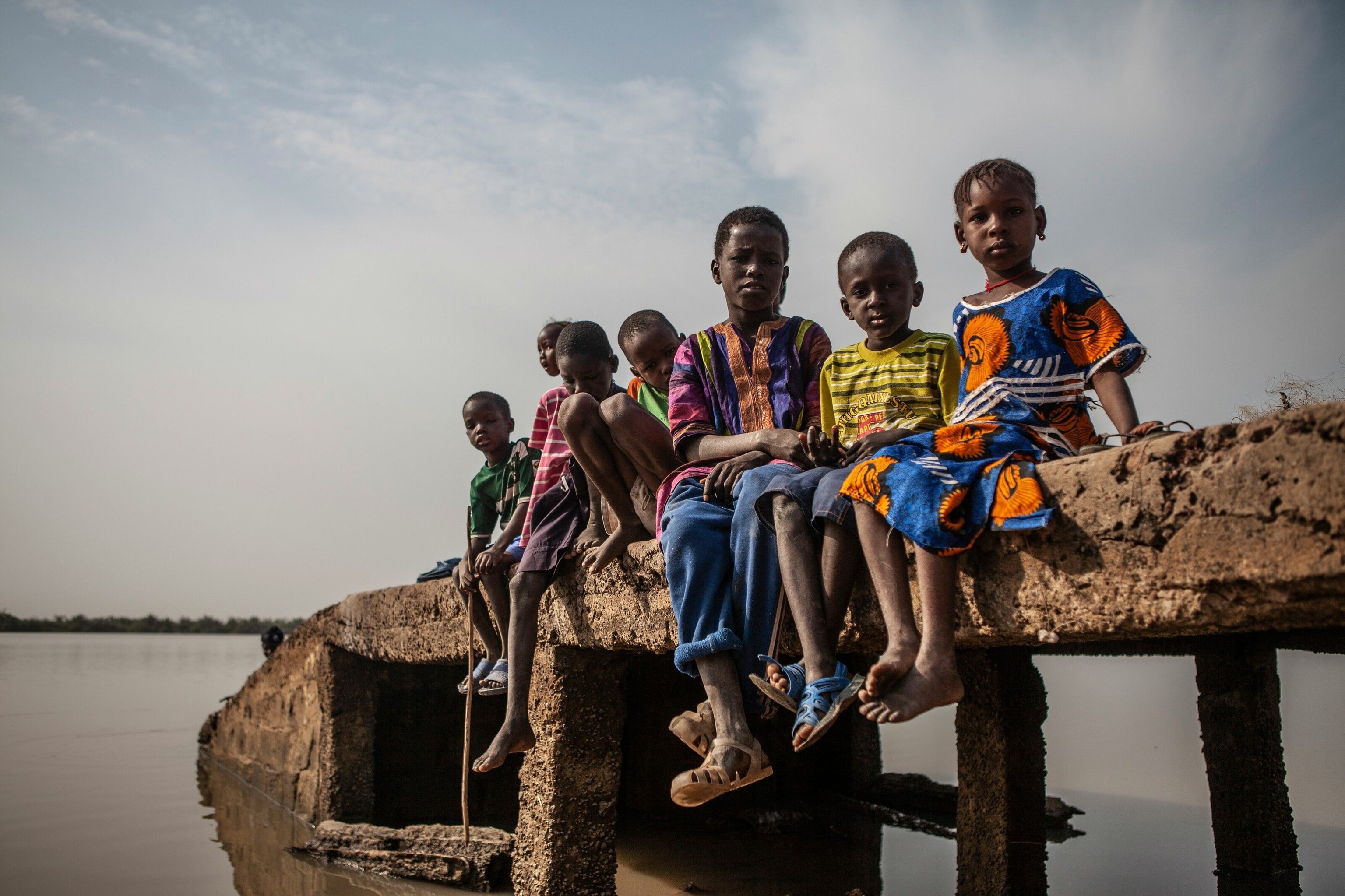 Children pose for a portrait on an old fishing jetty on River Gambia in the Upper River Region province.