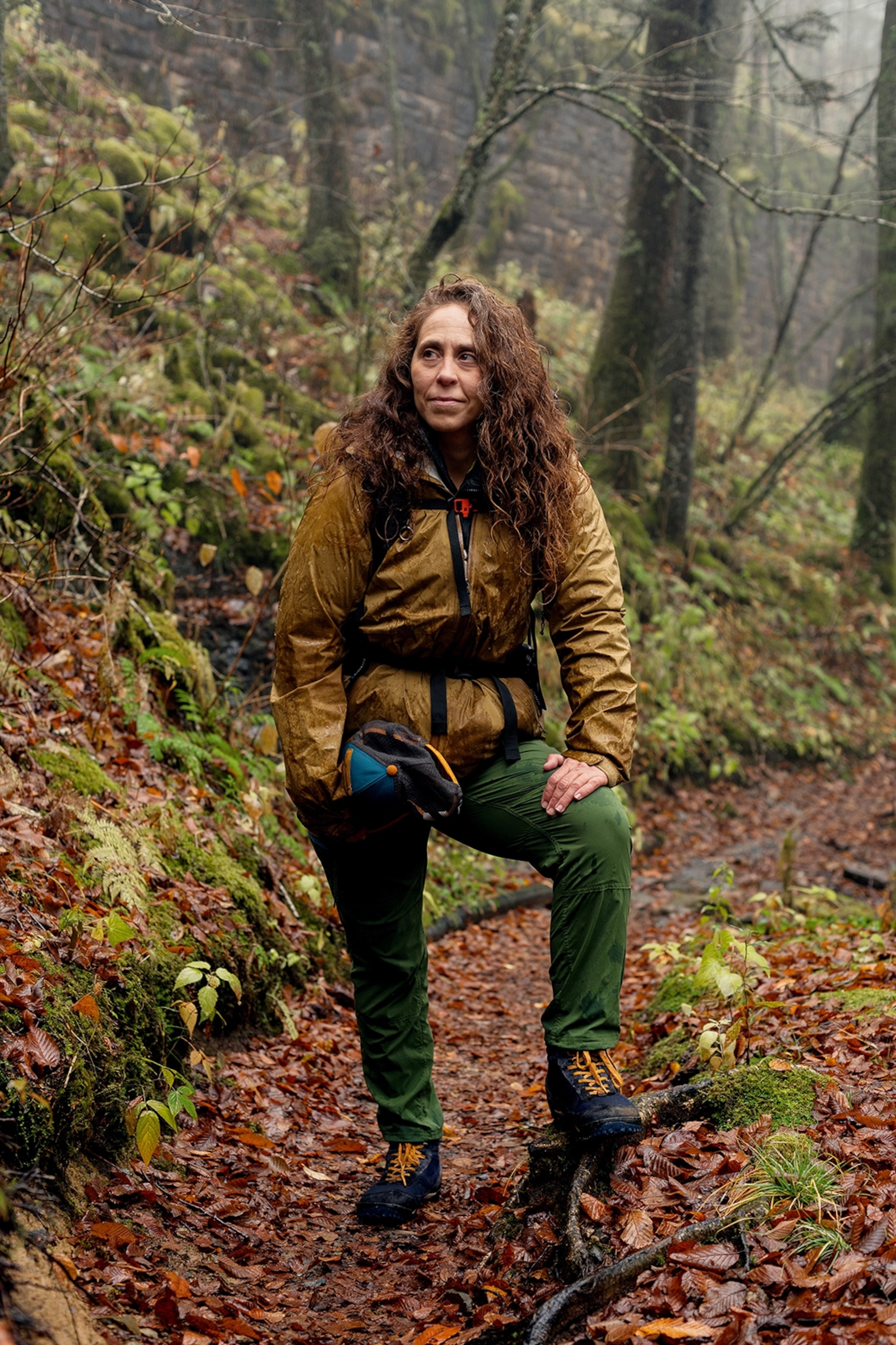 A young woman in hiking gear posing for a portrait on a hiking path surrounded by trees.