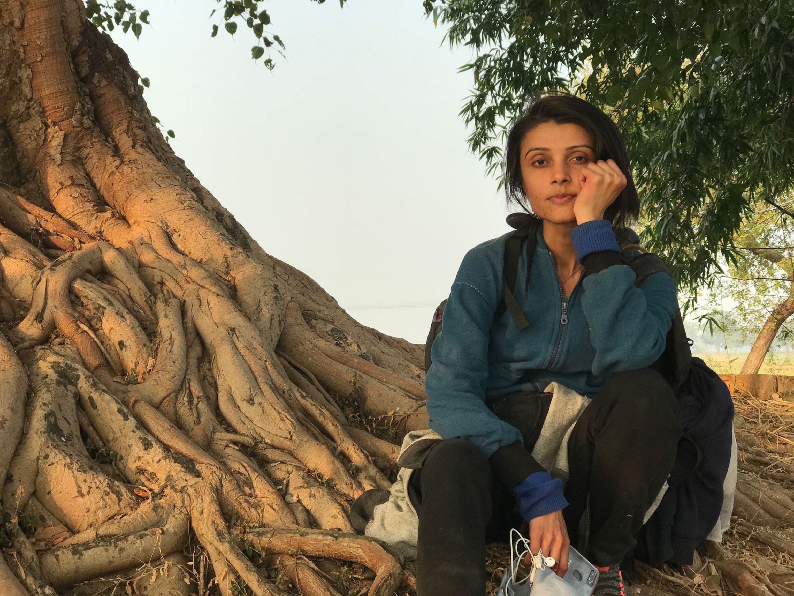 a woman posing at the base of a tree