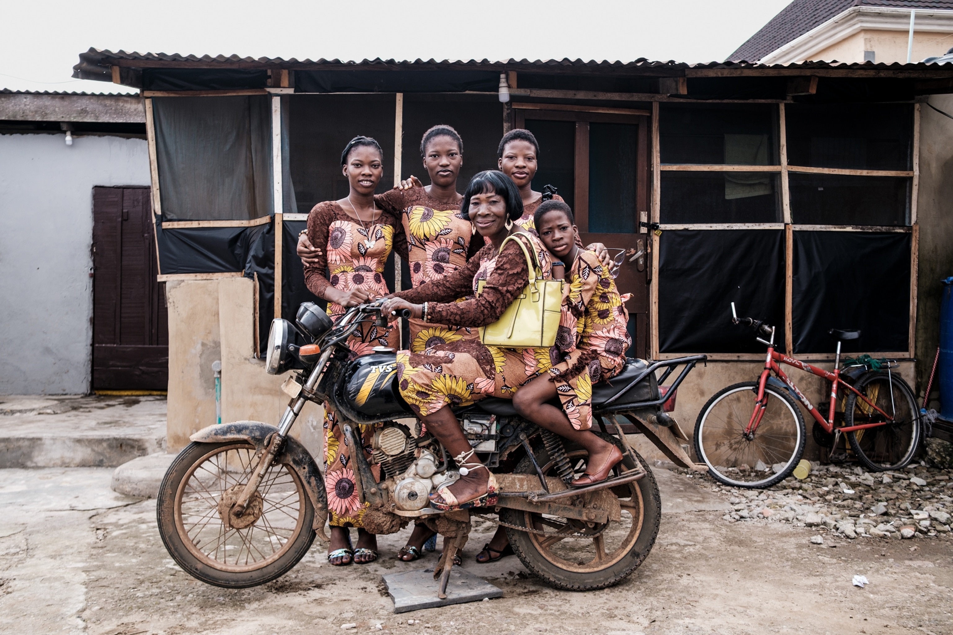 Woman on bike with four young women dressed into outfits from made from the same fabric.