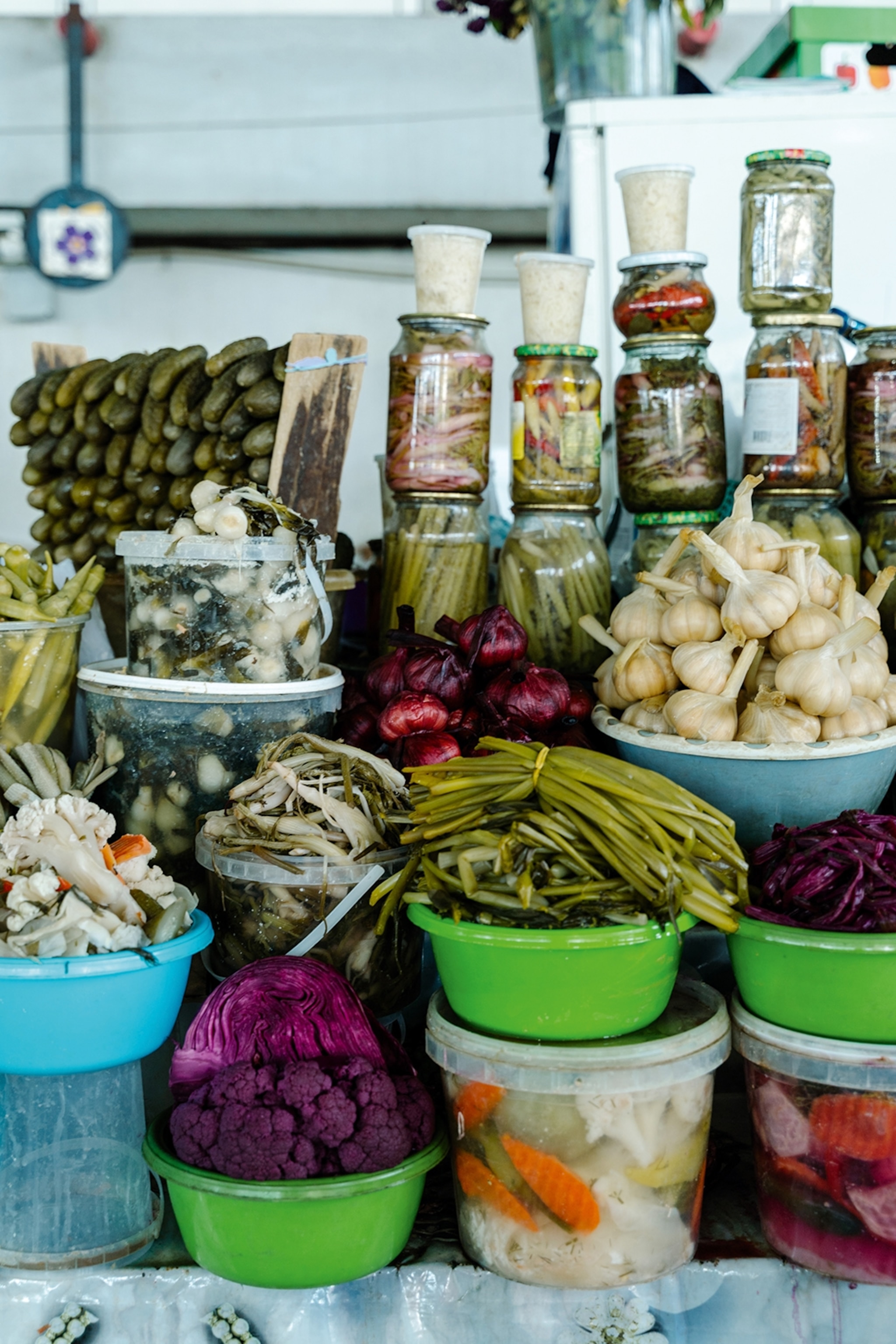 A market stall set up with jars of different pickles and bowls of more pickled vegetables in the foreground on multiple levels.