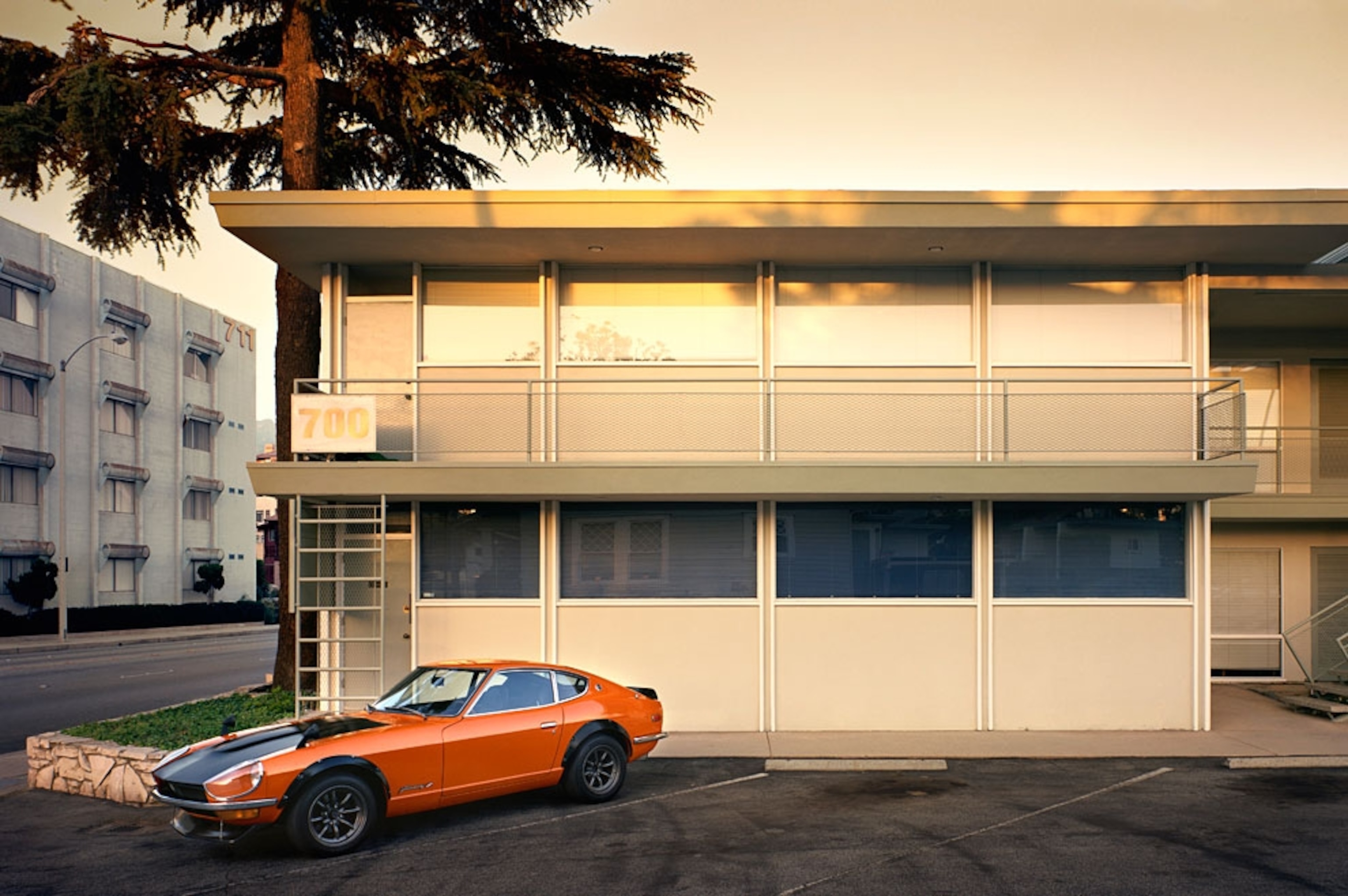 An orange Datsun 240Z parked in the city