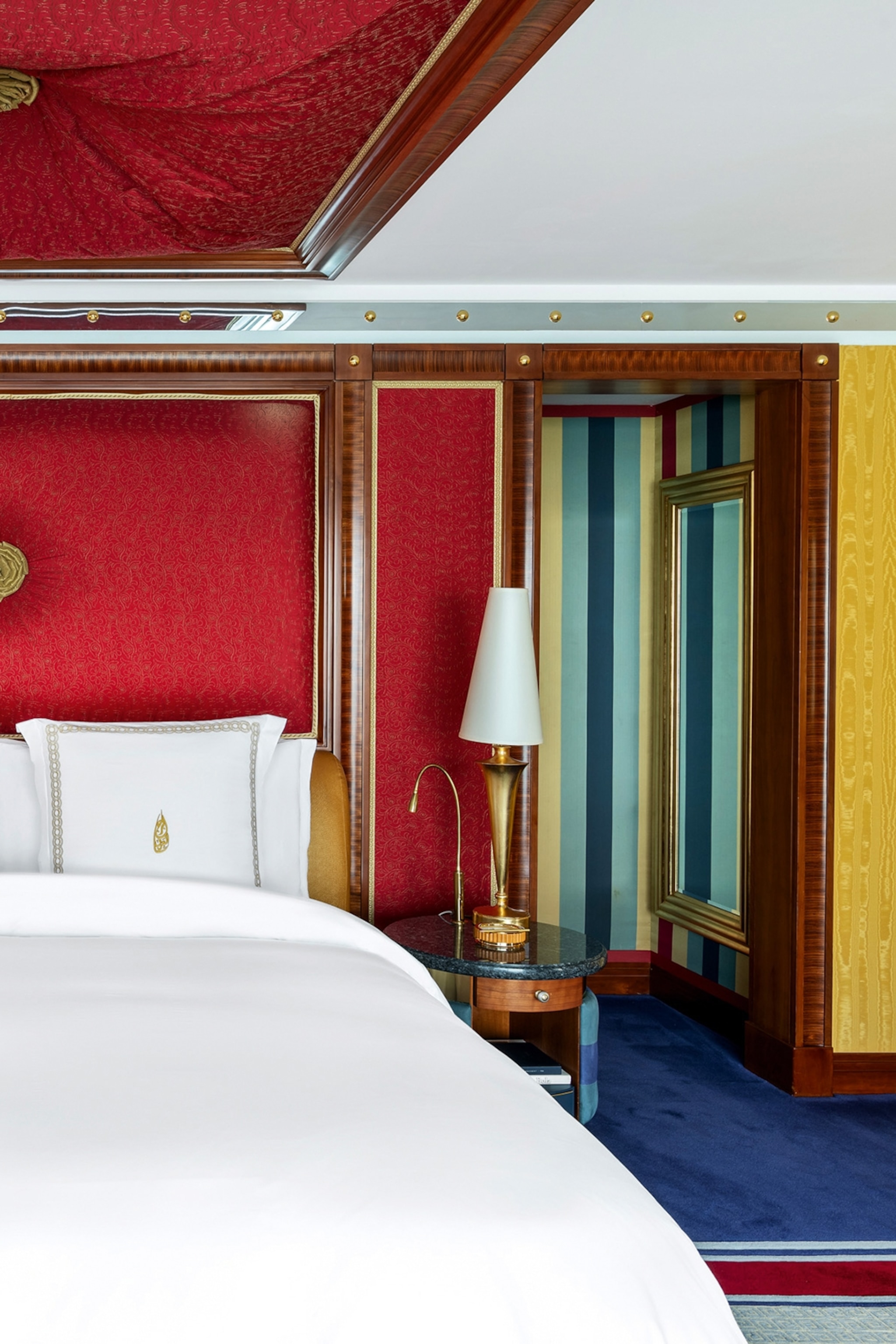 The interiors of a luxurious hotel bedroom with a padded ceiling, soft carpet and geometrically painted walls.