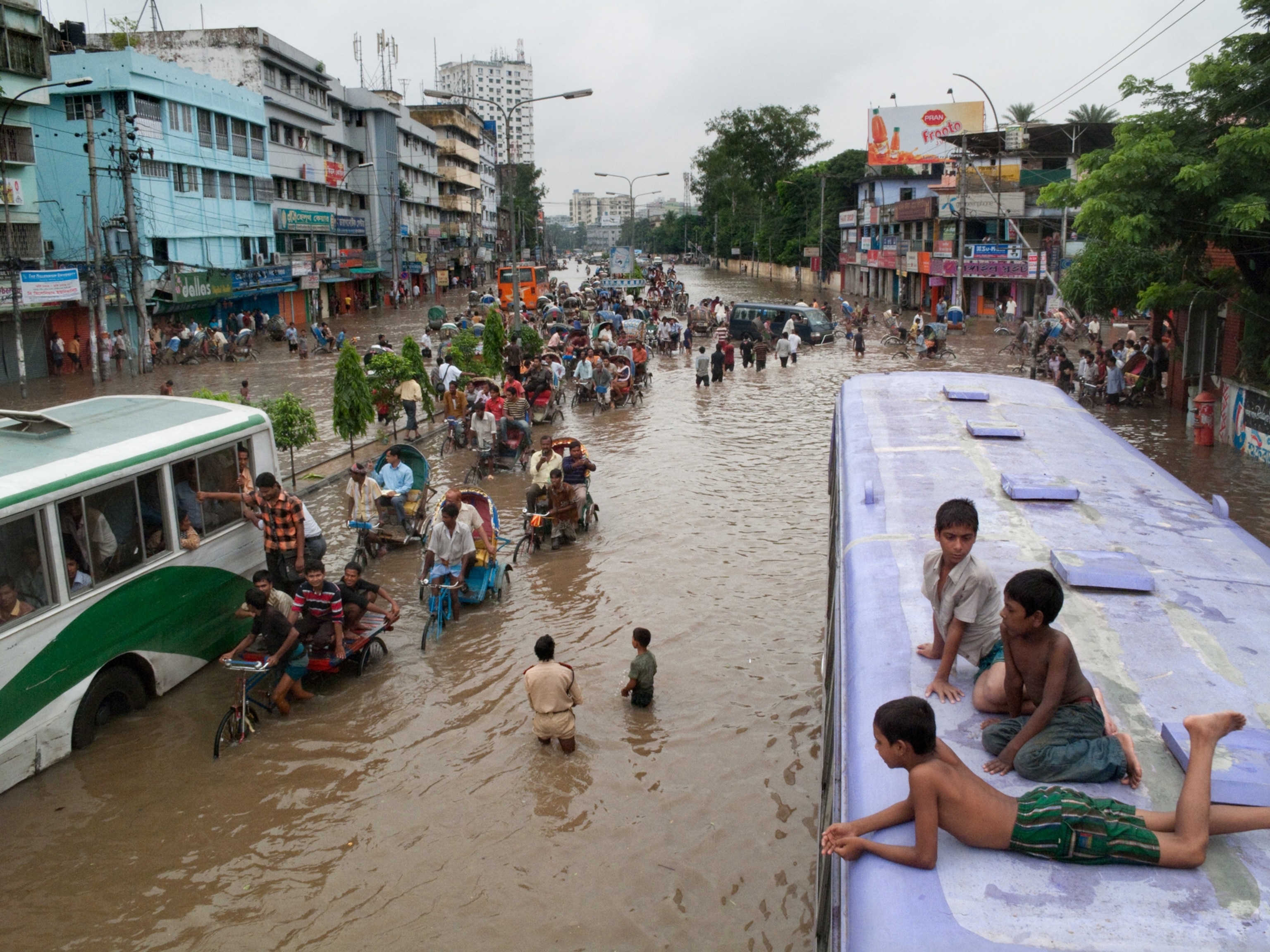 kids perched on a bus after flooding in Dhaka