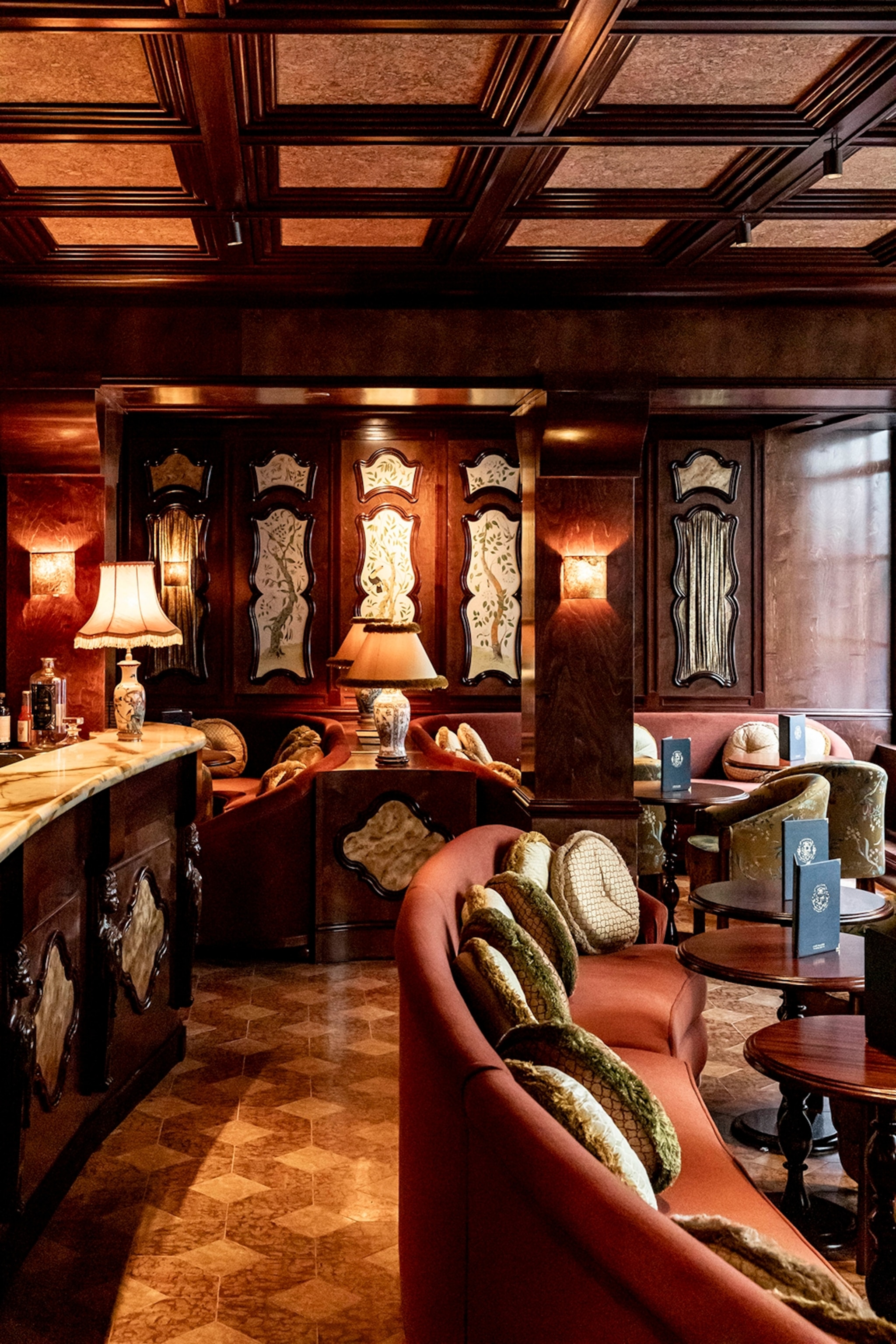 The interiors of an antique cafe in Paris with curved leather sofas and laquered walls.