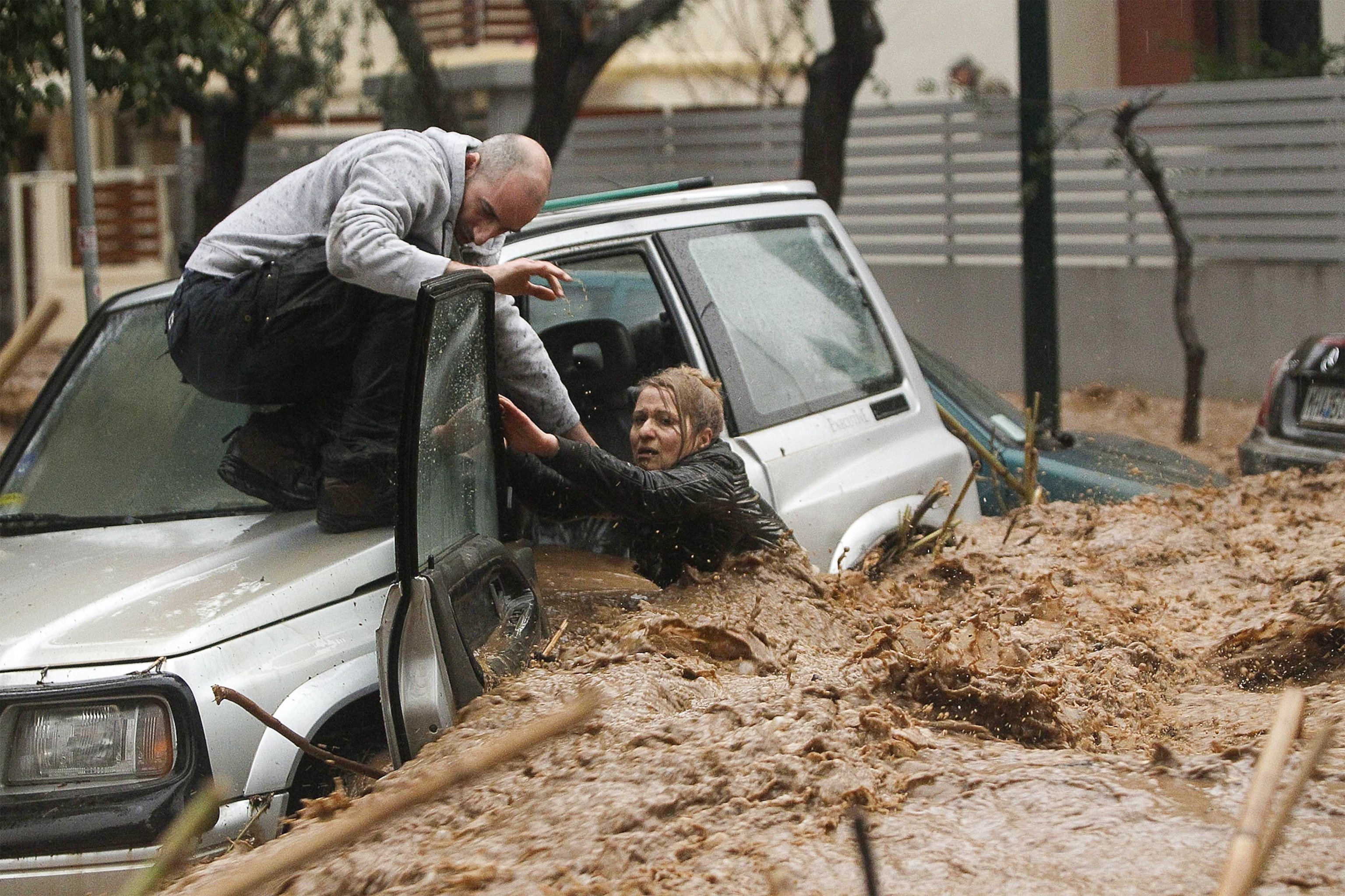 a man rescuing a woman from floodwater, Athens, Greece