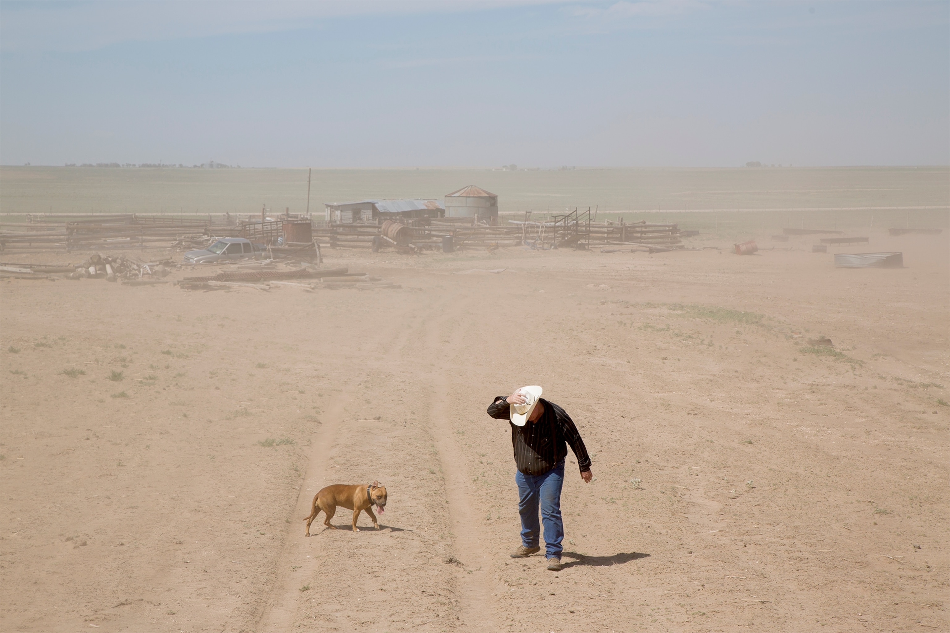 a farmer walking through a dust storm
