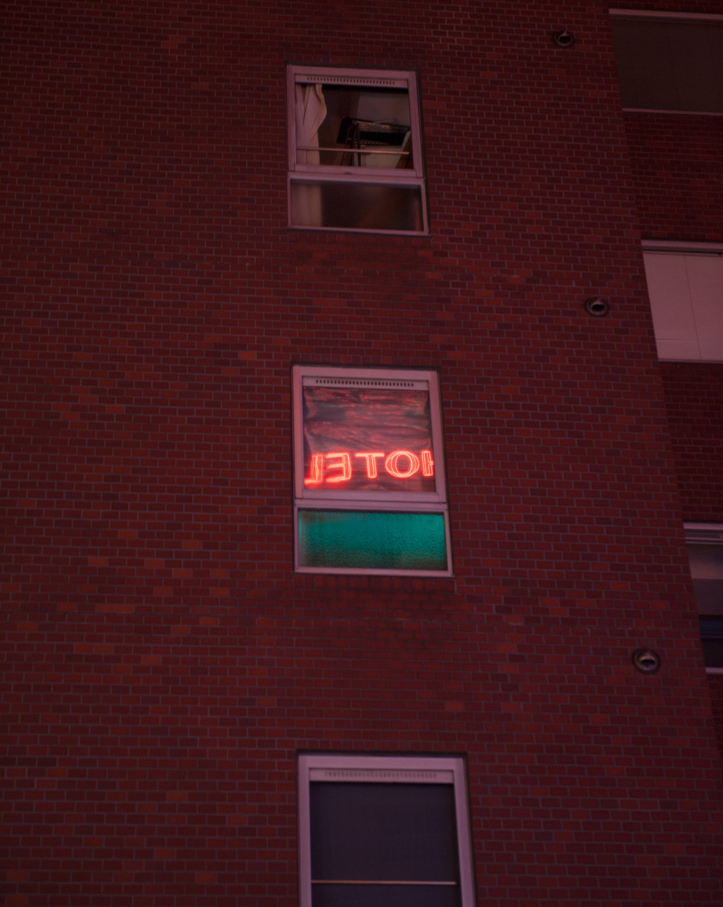 a window reflects a neon sign in the love hotel district in Tokyo, Japan