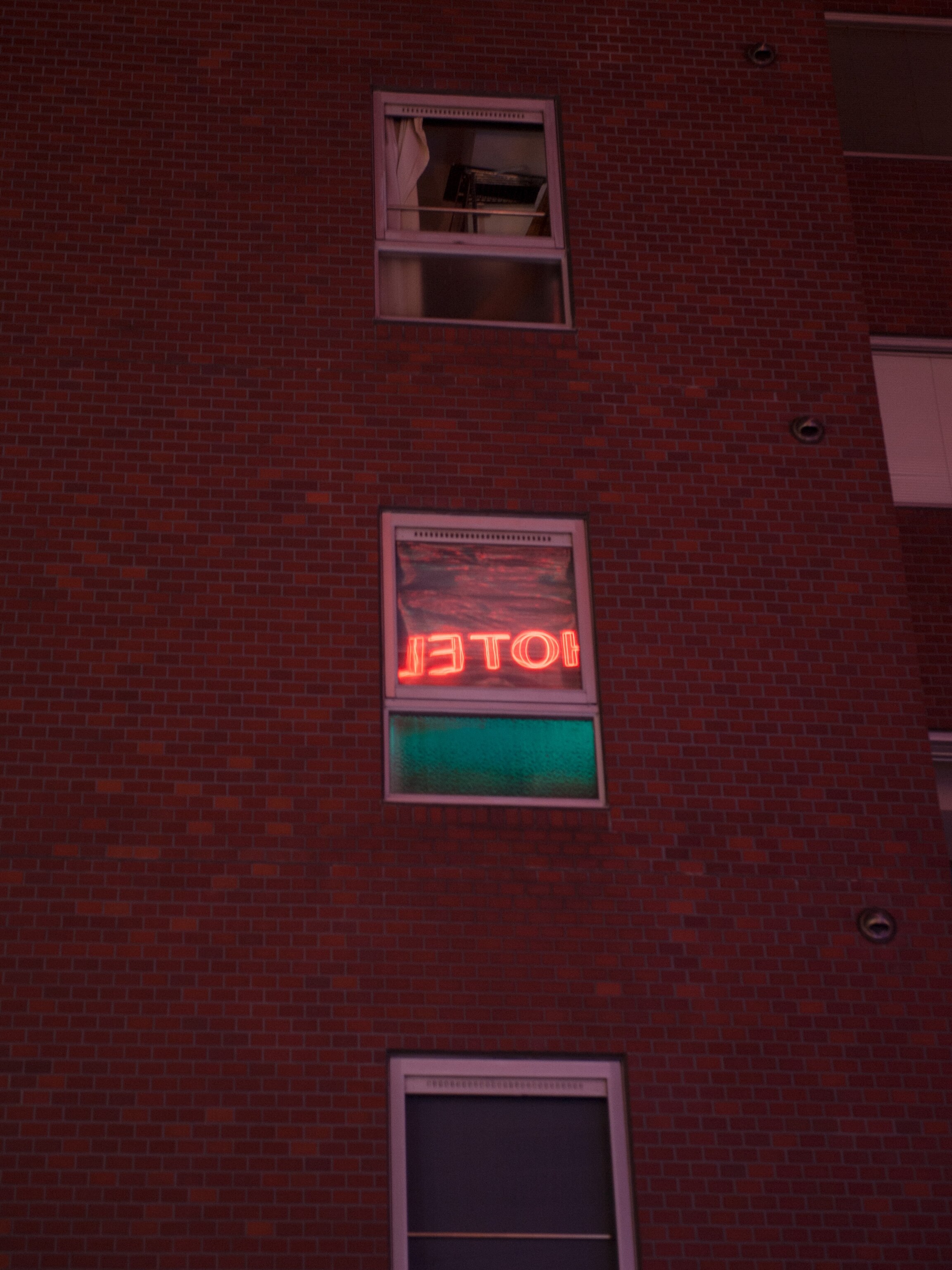 a window reflects a neon sign in the love hotel district in Tokyo, Japan