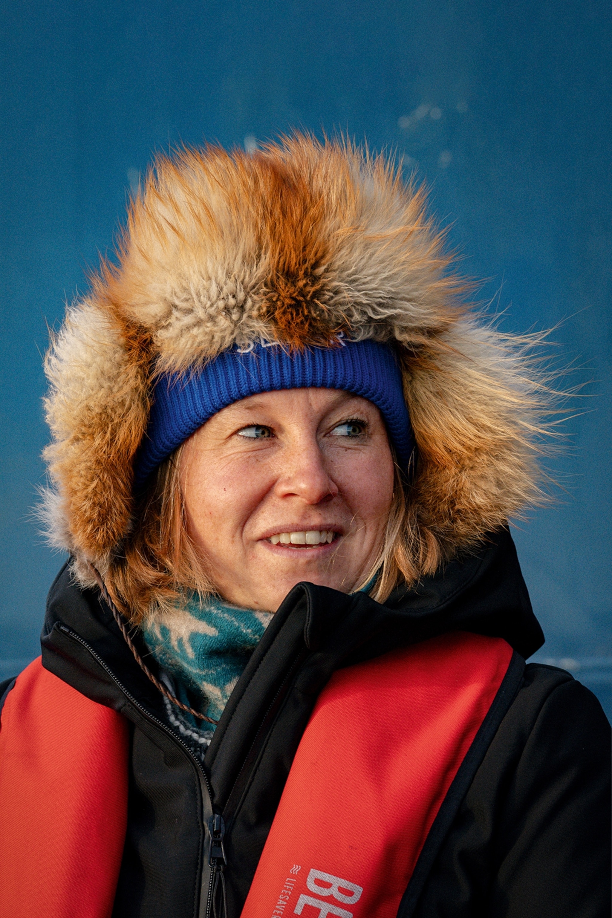 The portrait of a smiling woman wrapped in a fur hat and thick coat fit for arctic temperatures.