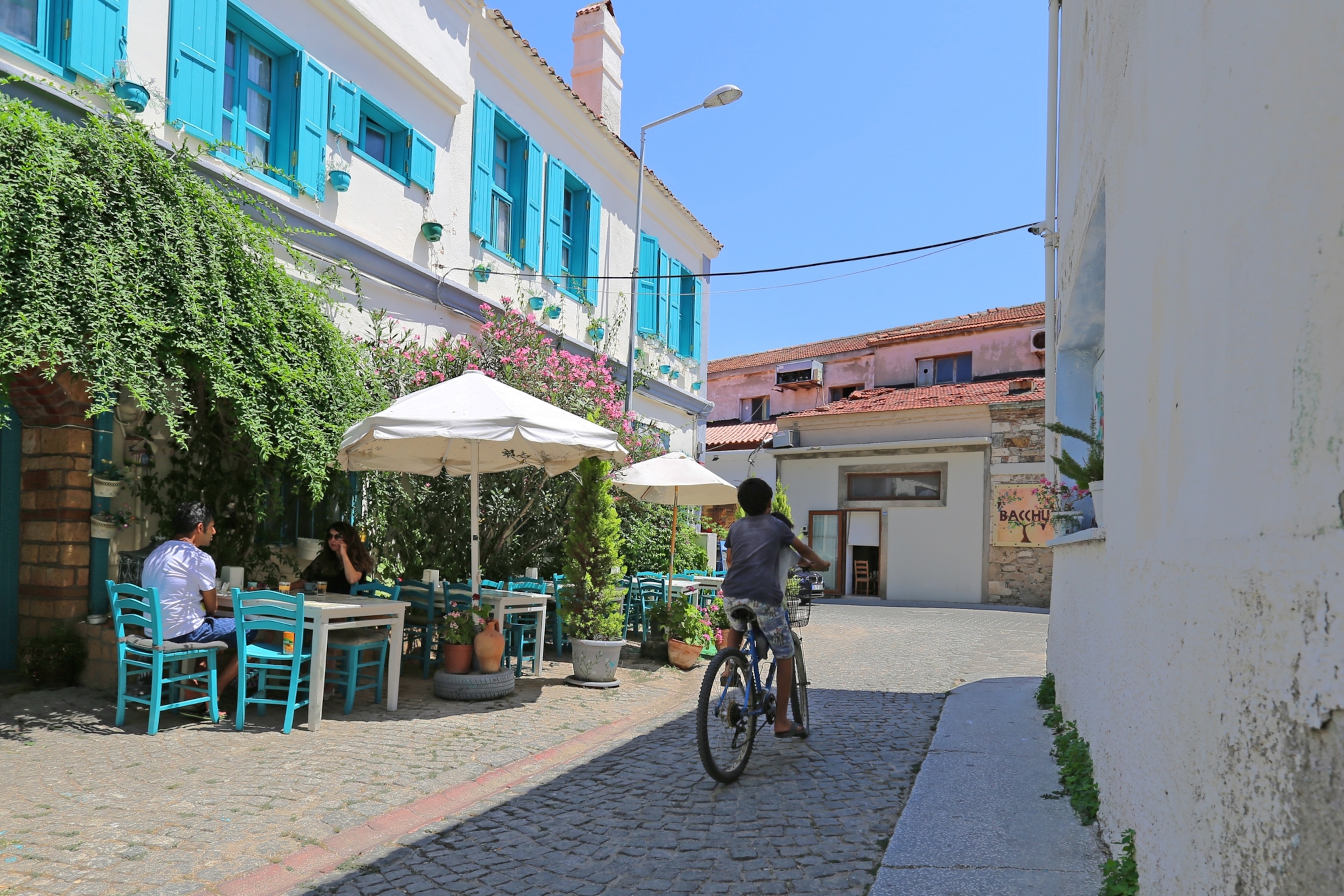 Youngsters on a bicycle by a cafe in Bozcaada, Turkey.