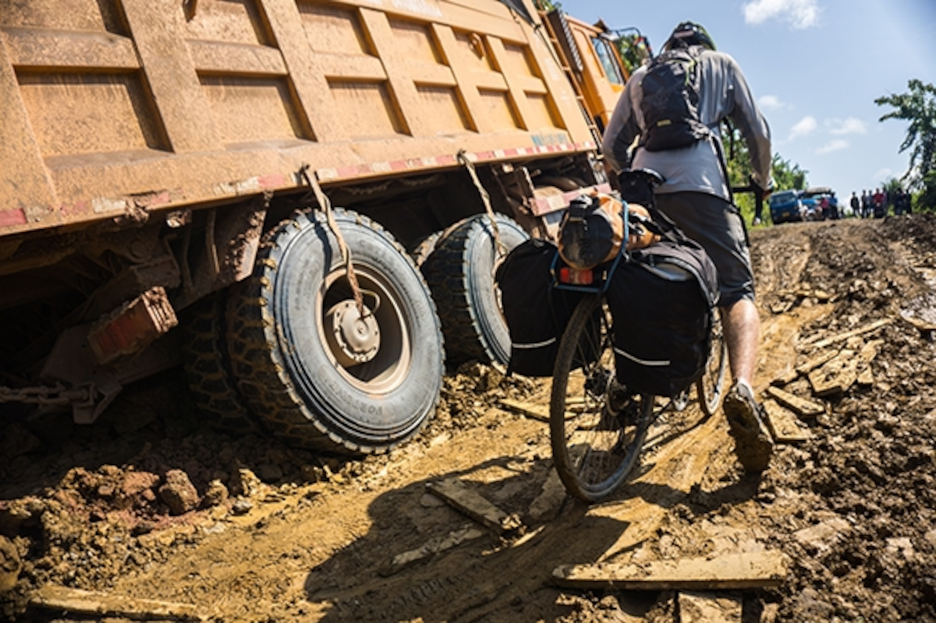 Will Stauffer-Norris wades through the muck that has caught these heavy duty Chinese trucks after a rainstorm. Bicycles prove to be more wieldy in this friction of terrain. Photograph by Kyle Hemes