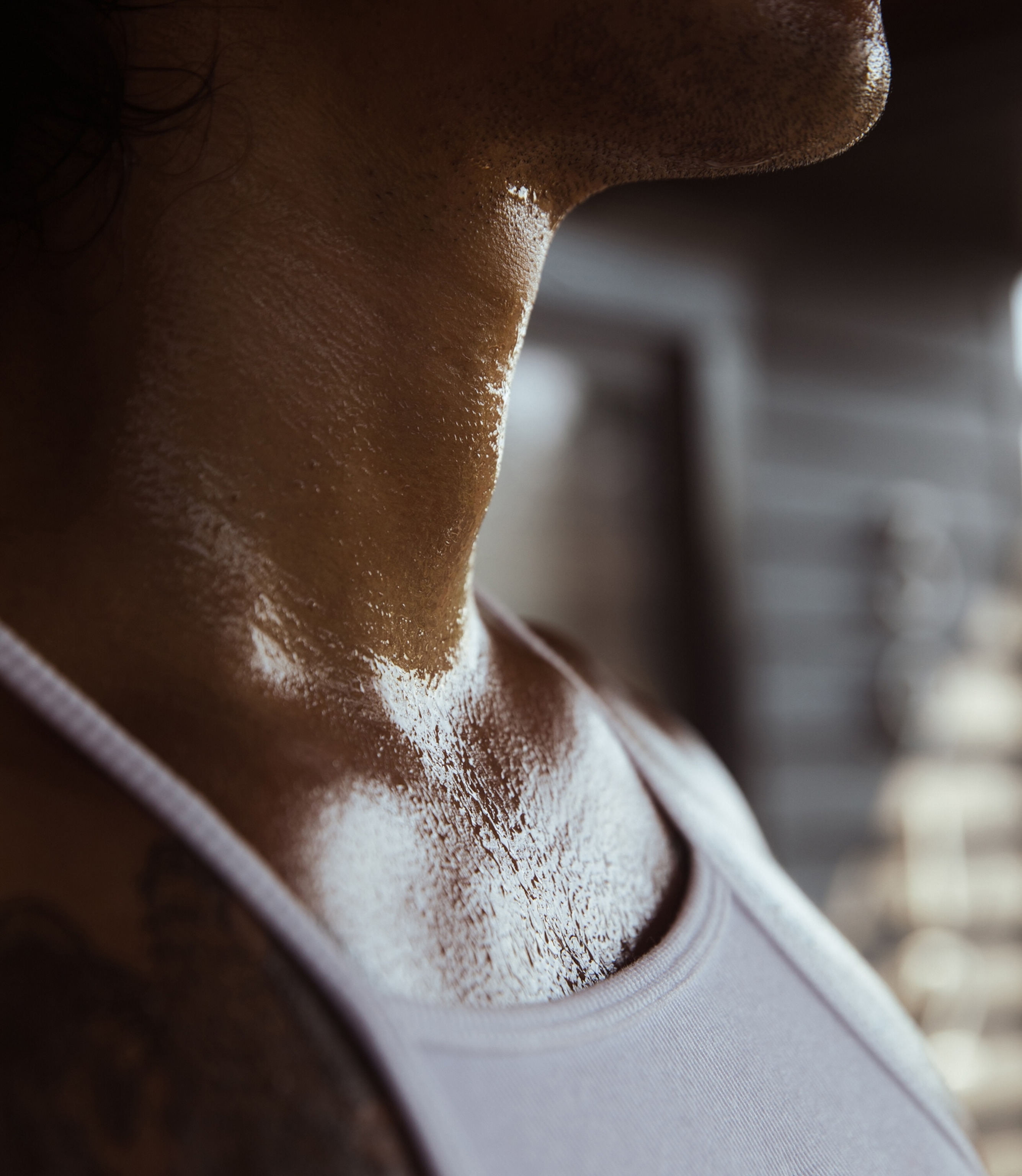 Close-up of a person's neck and chin, glistening with sweat, wearing a tank top
