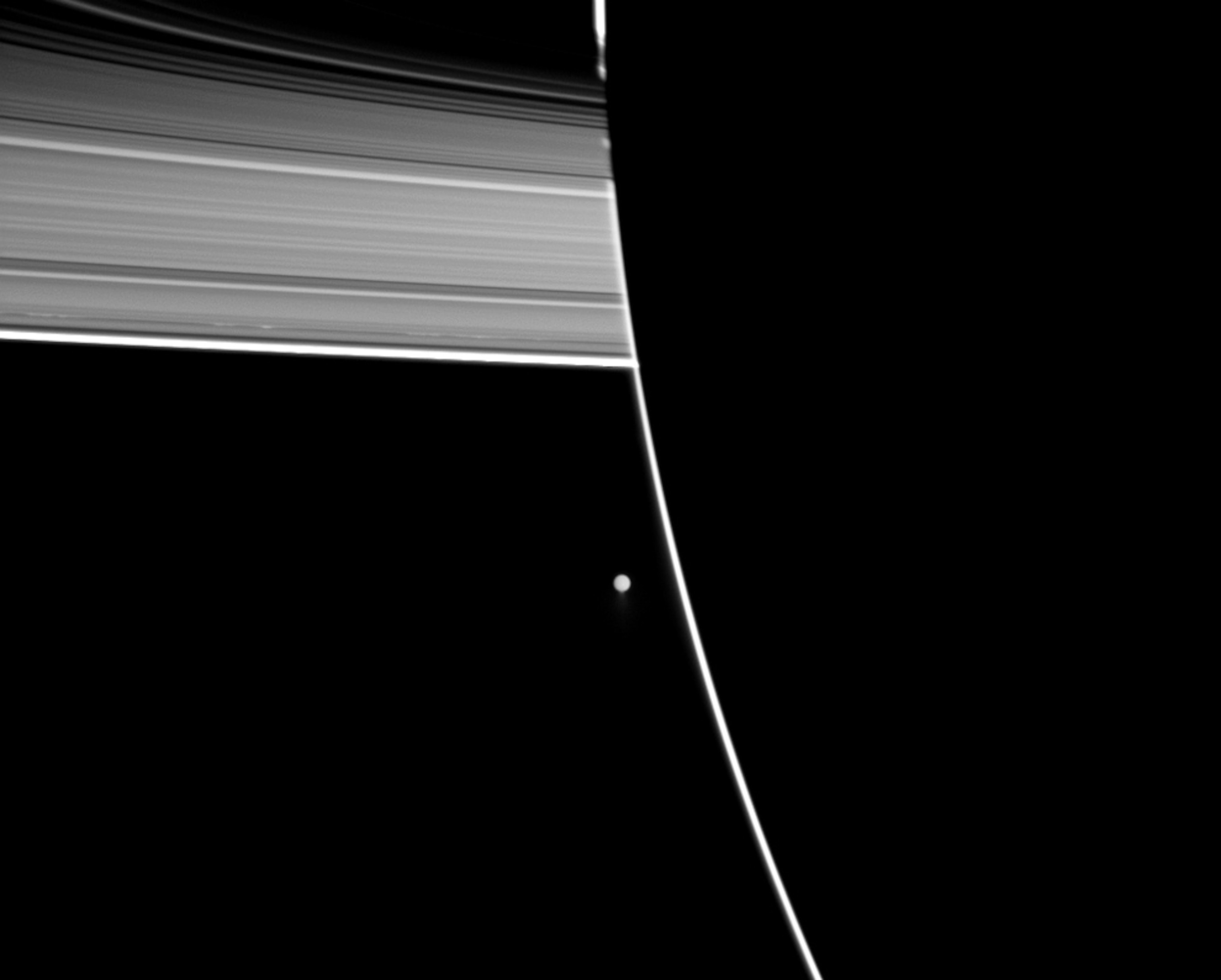 Picture of the night side of Saturn with part of the rings and the moon Enceladus in the background.