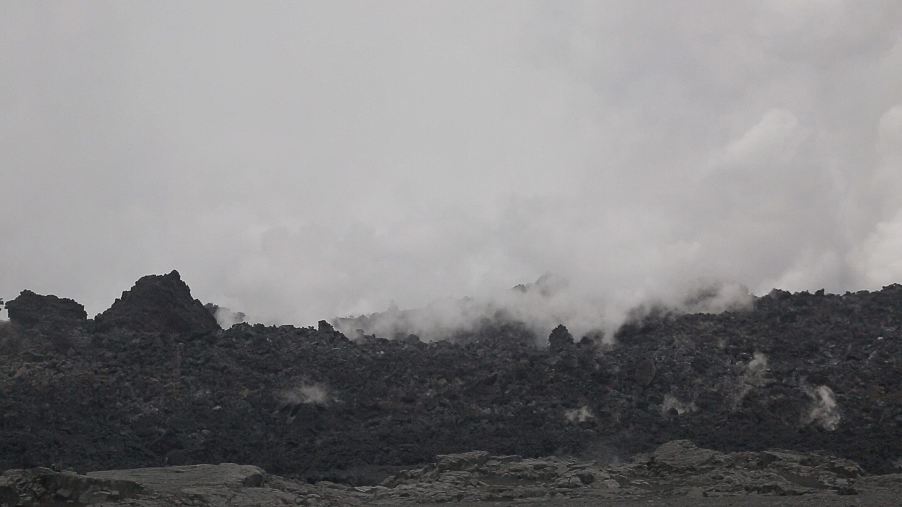 smoke rising up from fields of black lava