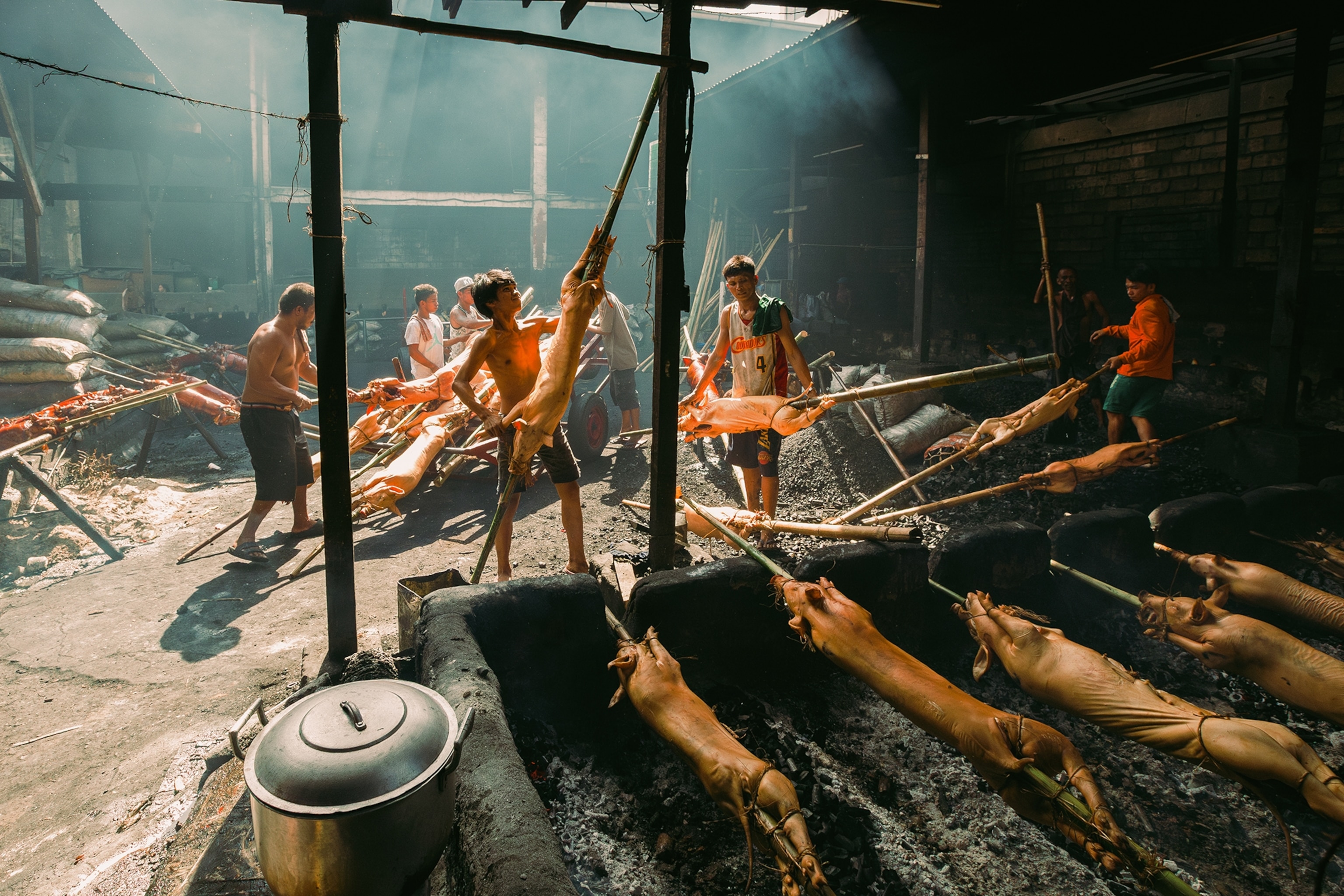 A griller picks newly delivered raw pork to be cooked on an open fire grill at La Loma, Metro Manila, Philippines. Lechon is a typical holiday or celebration cuisine that is culturally popular in the country. Whether be it a celebration, an event, or during Christmas, there's a celebration when there is lechon on the table.